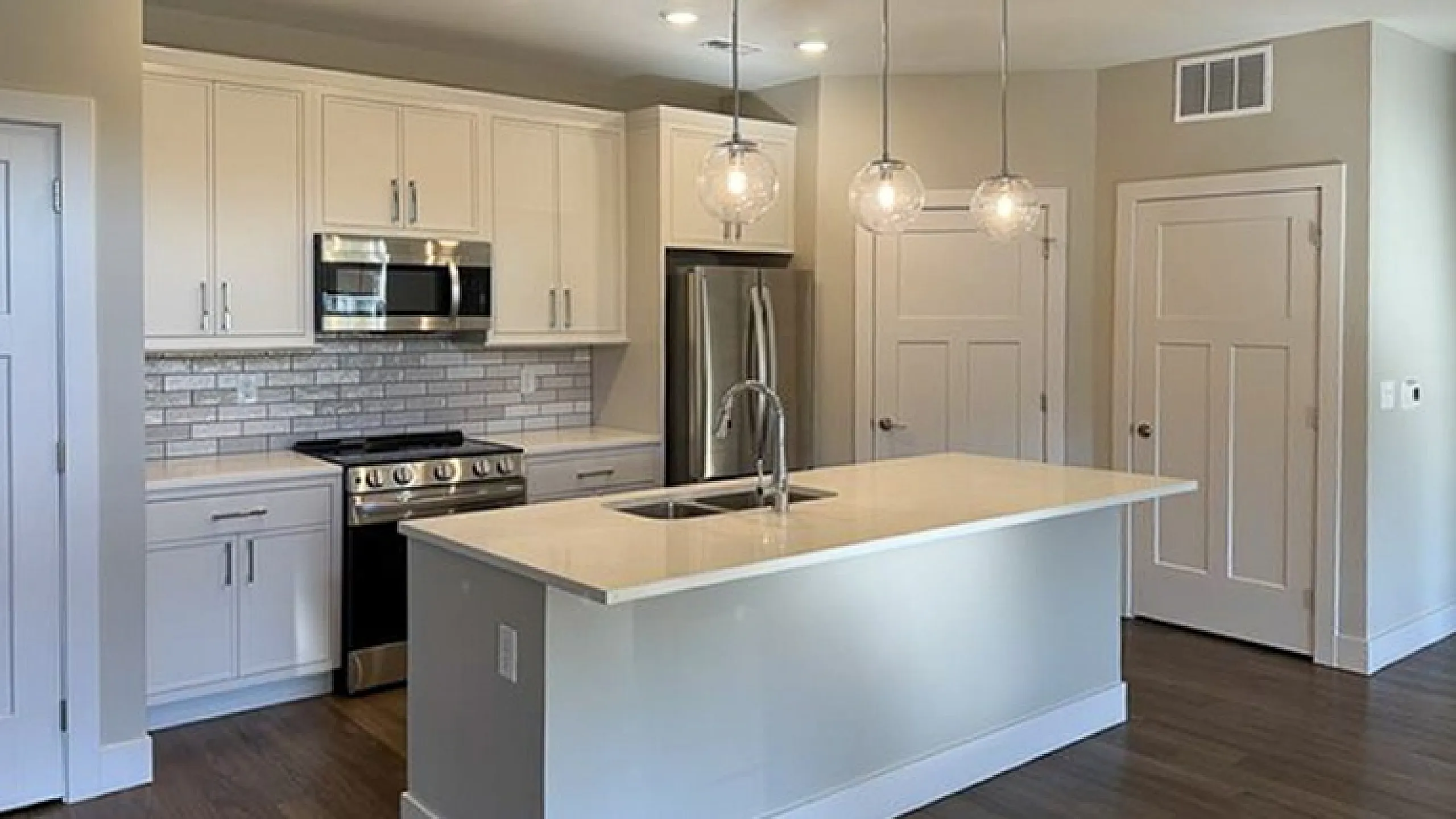 Modern kitchen with sleek white cabinets, stainless steel appliances, and elegant pendant lighting over a chic island.
