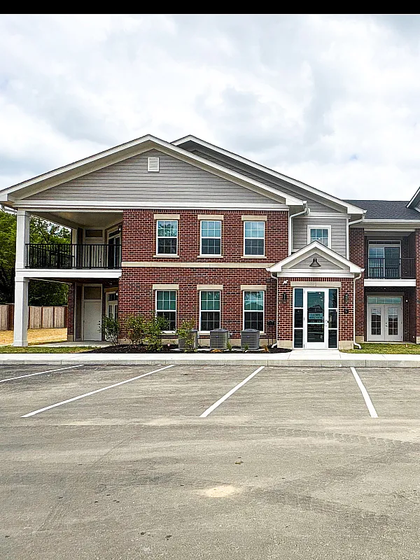 Charming two-story brick apartment complex with elegant architecture, featuring ample parking and lush landscaping.
