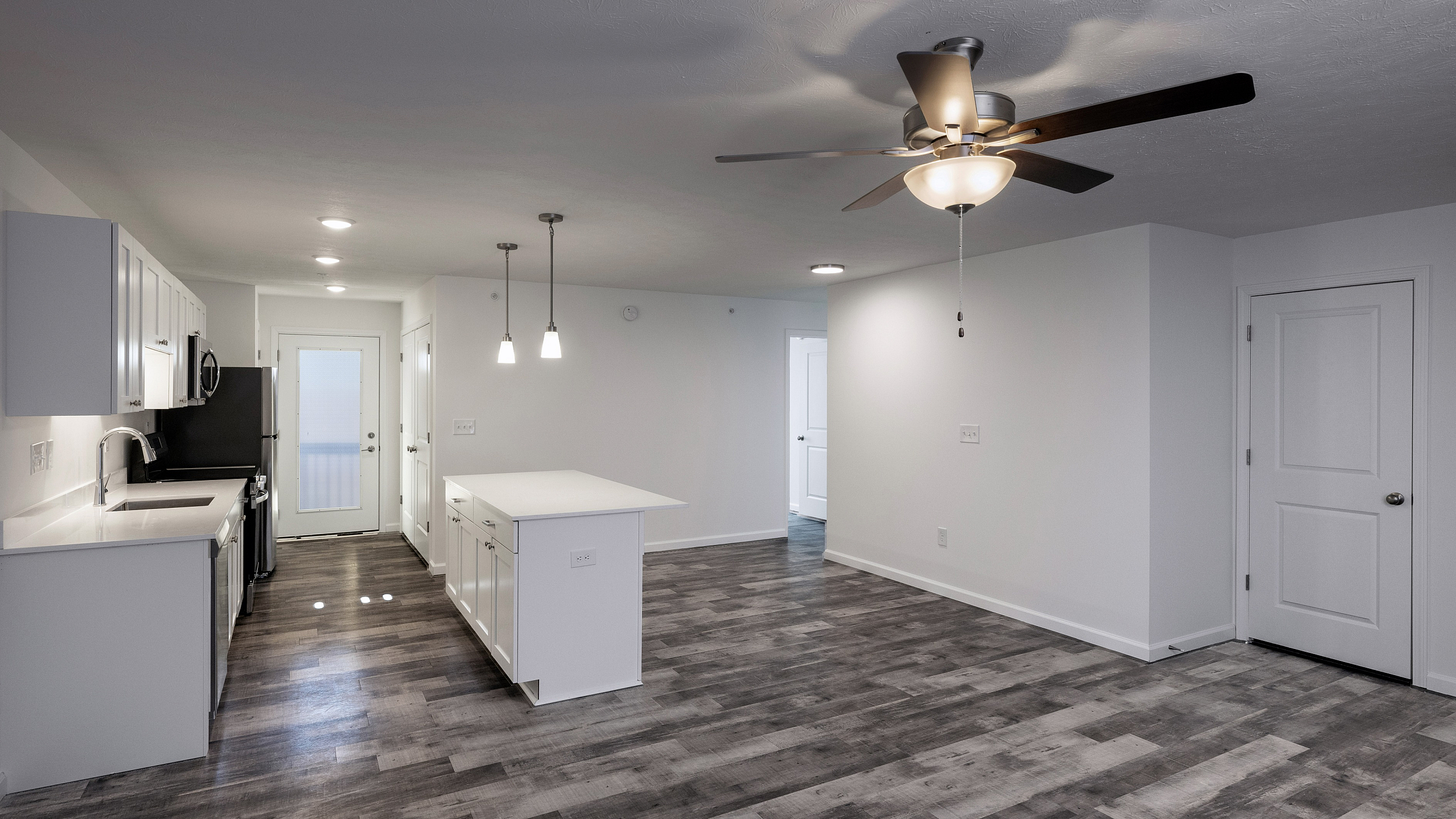 Modern open-concept living area with sleek kitchen, elegant island, and contemporary lighting fixtures.