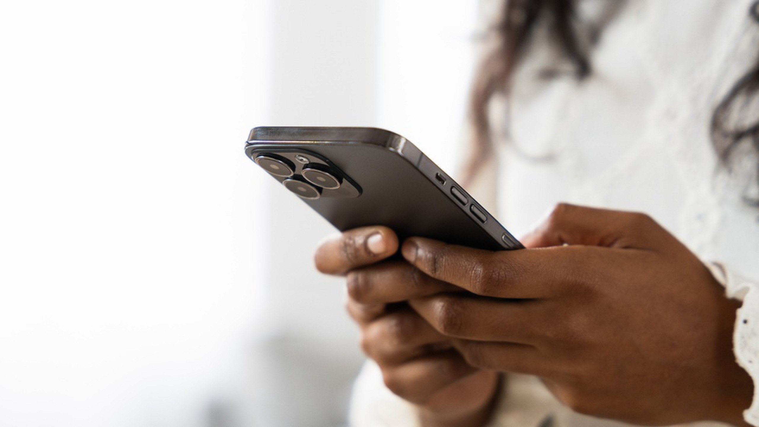 Close-up of a person holding a modern smartphone with a sleek design, highlighting the device's advanced camera features.