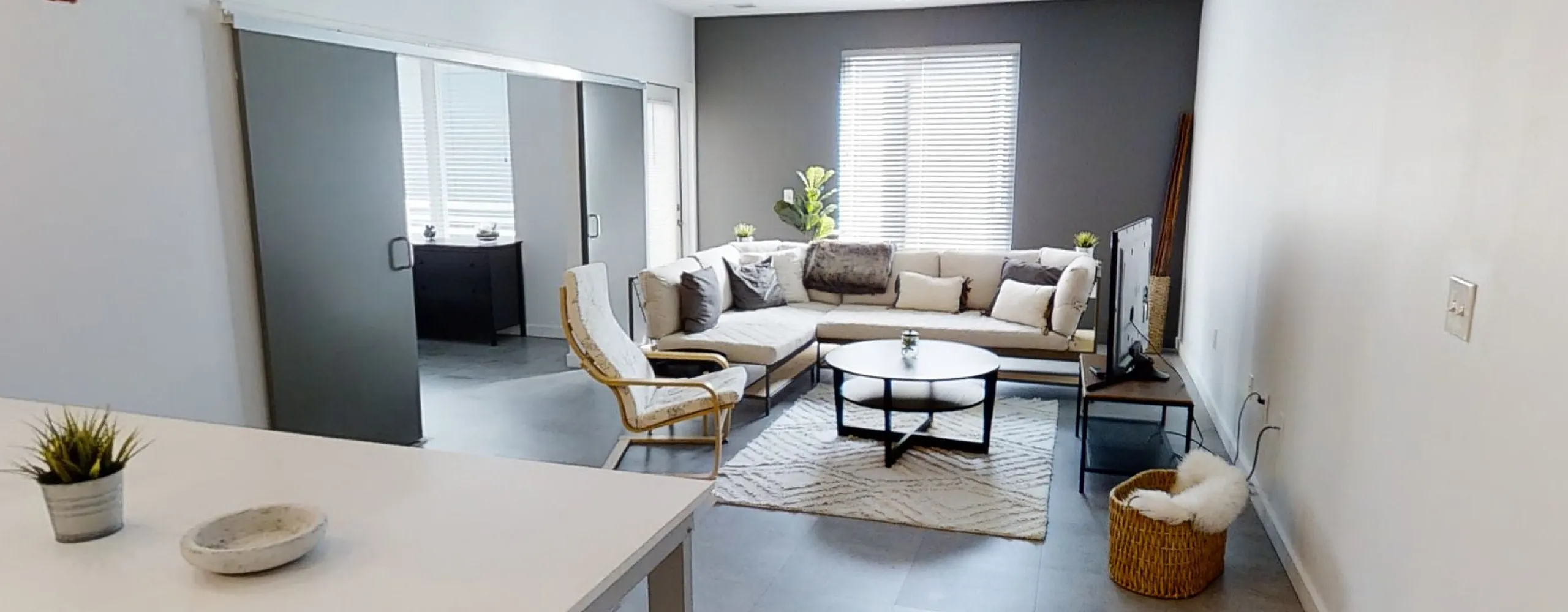 Modern living room with stylish L-shaped sofa, chic armchair, and bright natural light.