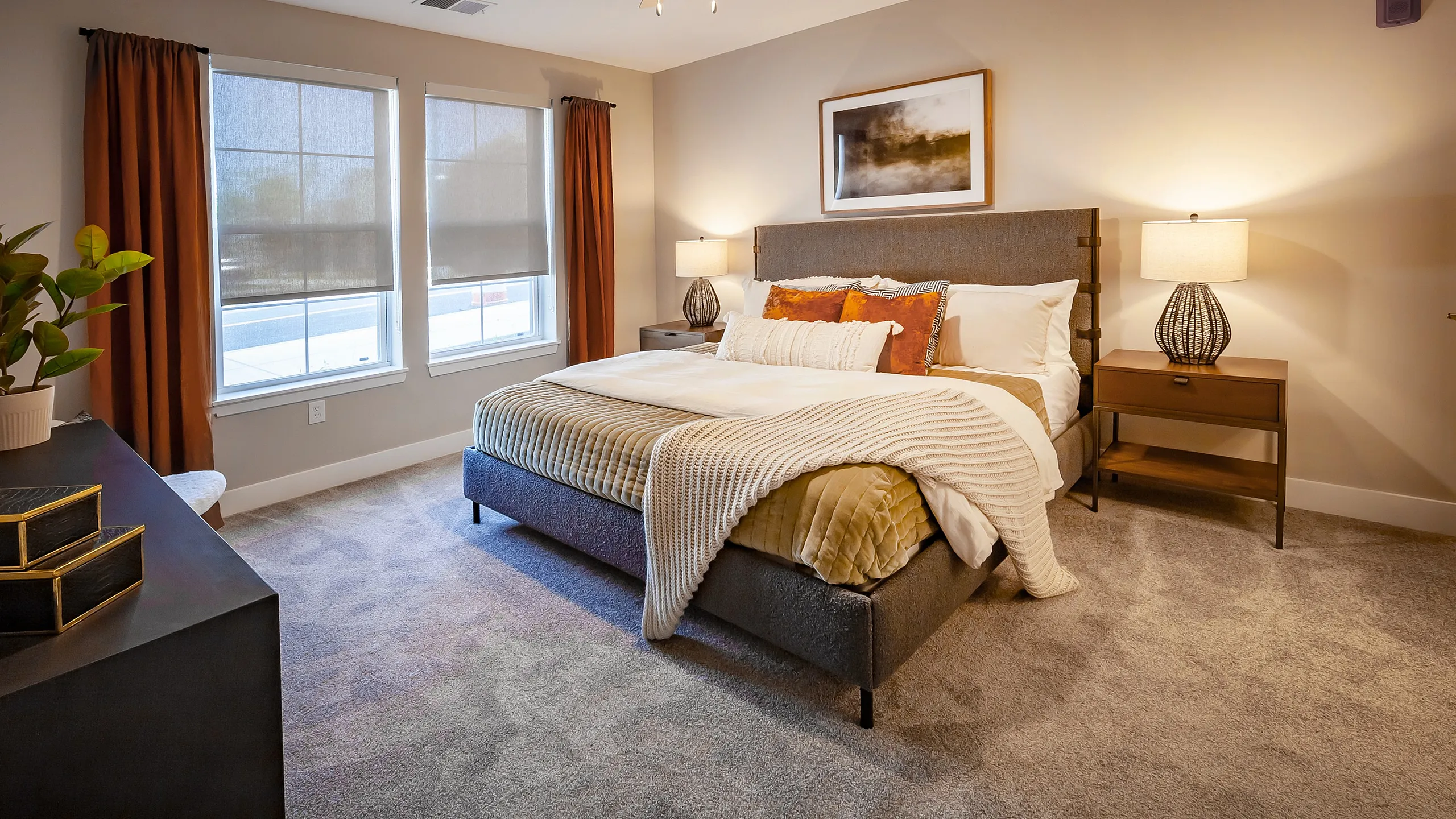 Inviting bedroom with plush carpet, a cozy double bed, and warm lighting, featuring modern decor and large windows with elegant drapes.