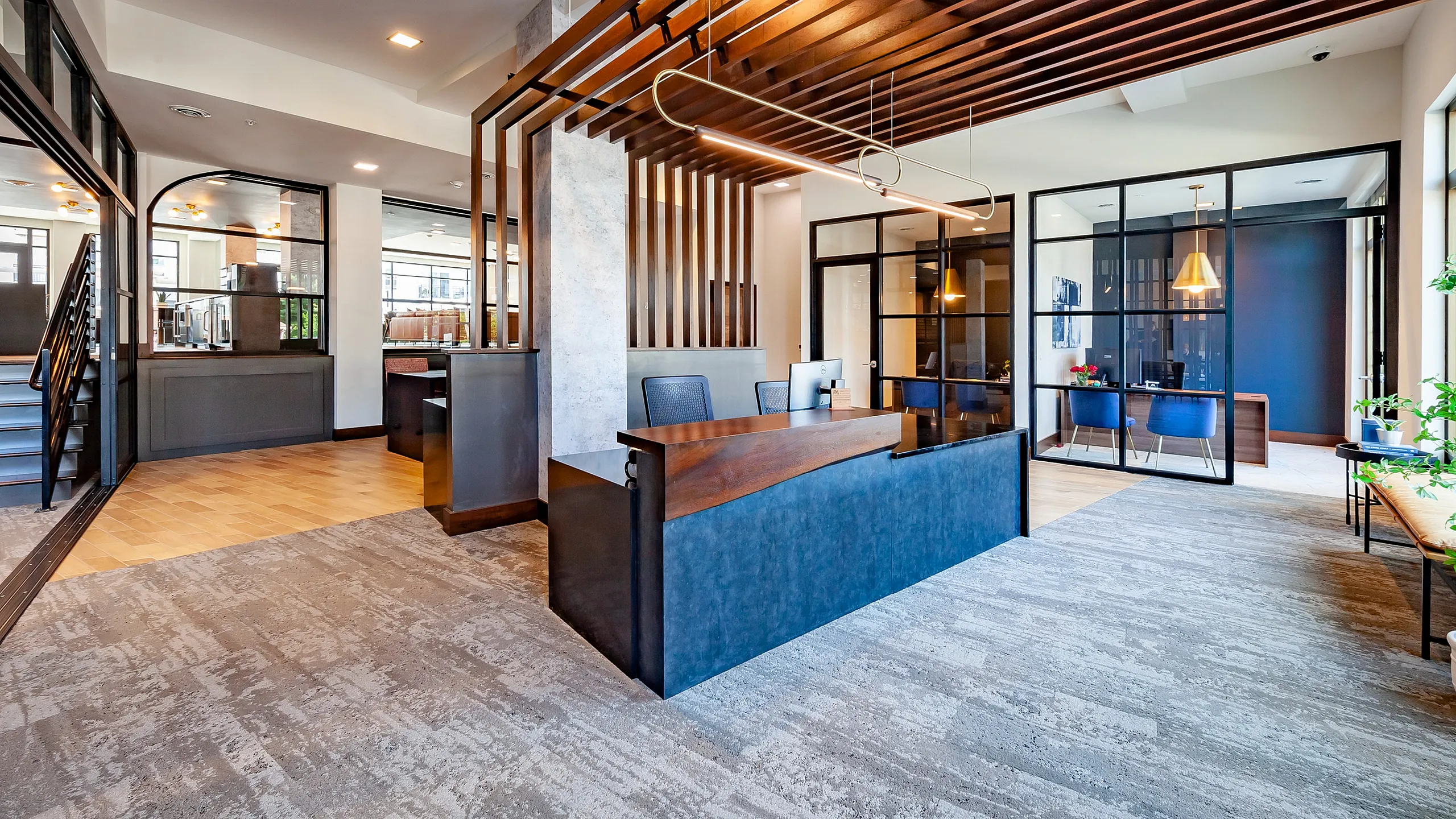 Modern, spacious office lobby featuring elegant wood accents, large glass windows, and stylish contemporary furniture.