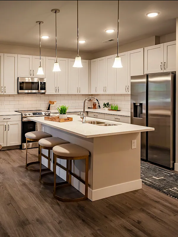Chic modern kitchen with sleek white cabinetry, spacious island with bar seating, and stylish pendant lighting.