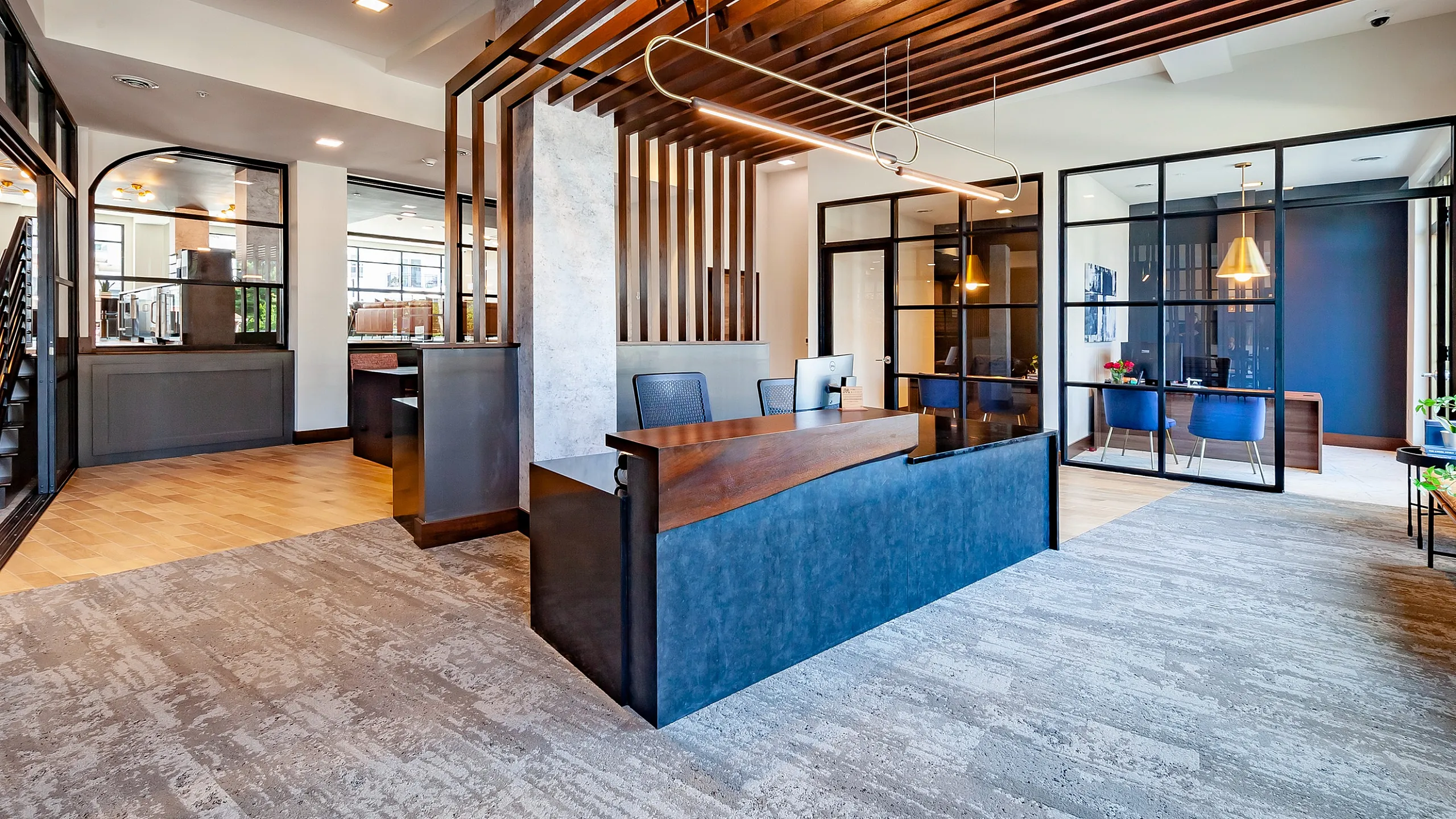 Contemporary office space with sleek wooden accents, modern reception area, and glass-enclosed private rooms.