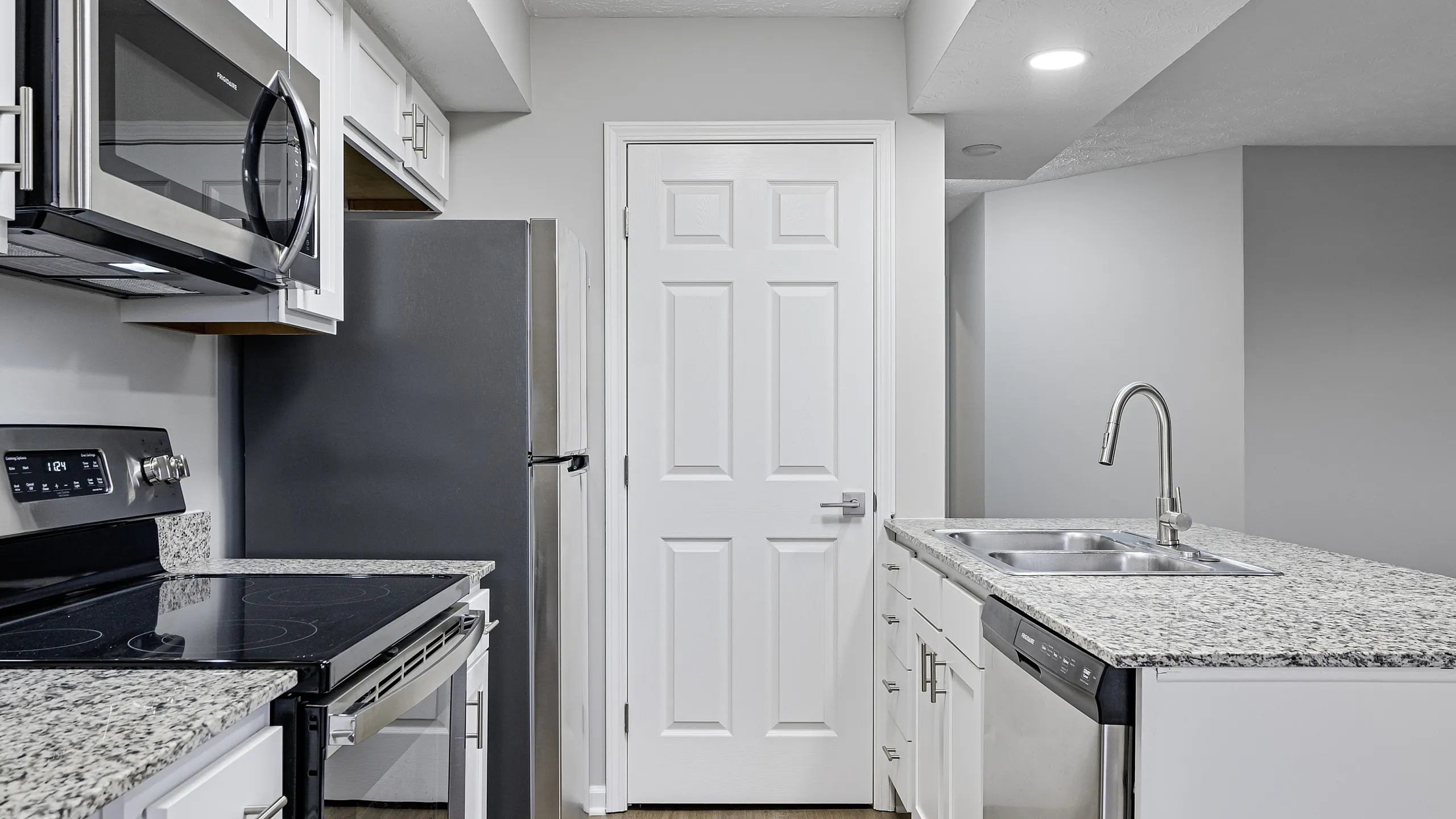 Contemporary kitchen with sleek stainless steel appliances, modern white cabinetry, and a chic granite countertop.
