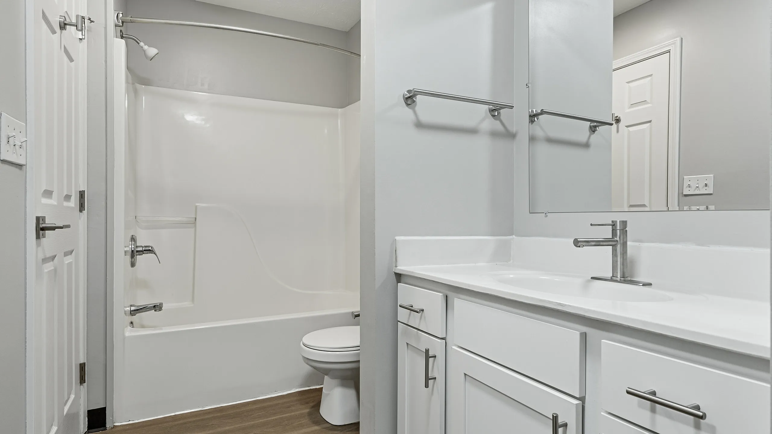 Modern bathroom featuring sleek white cabinetry, a spacious countertop, and elegant wood-look flooring.