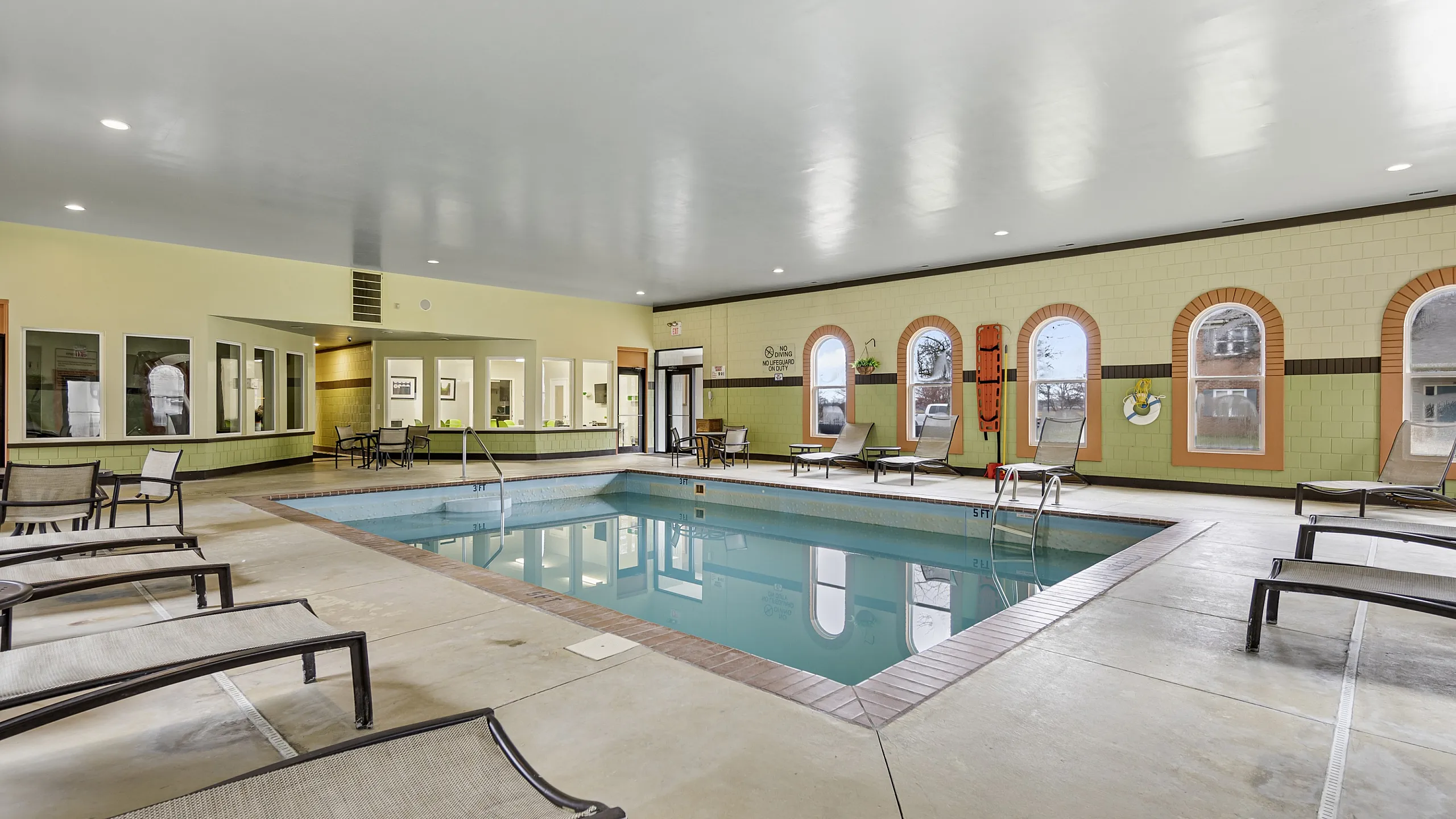 Spacious indoor pool area with elegant lounge chairs and ambient lighting, perfect for relaxation and leisure.