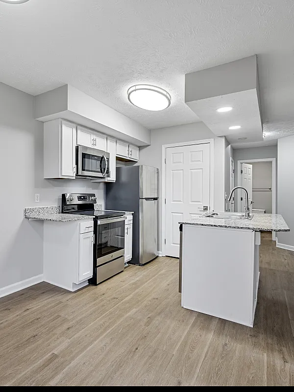 Modern kitchen with sleek stainless steel appliances and stylish granite countertops, complemented by elegant gray cabinetry and hardwood flooring.