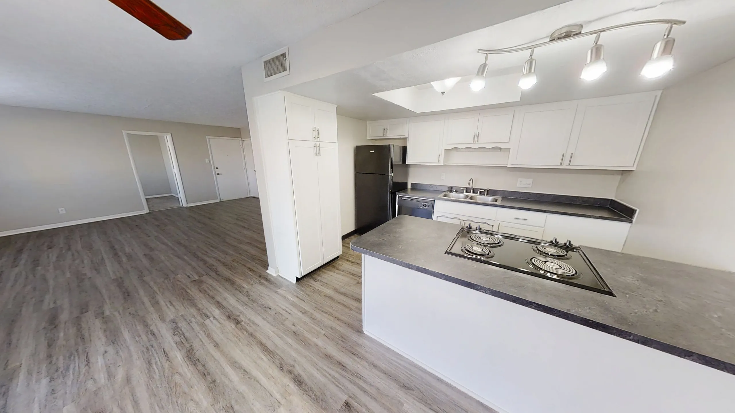 Inviting open-concept living space with modern kitchen, featuring sleek countertops, stainless steel appliances, and elegant wood flooring.