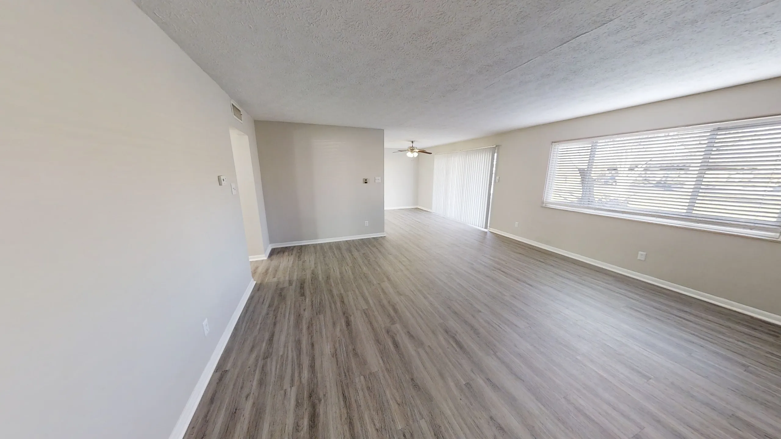 Chic and spacious living area with elegant wood flooring, large windows offering natural light, and seamless open layout.