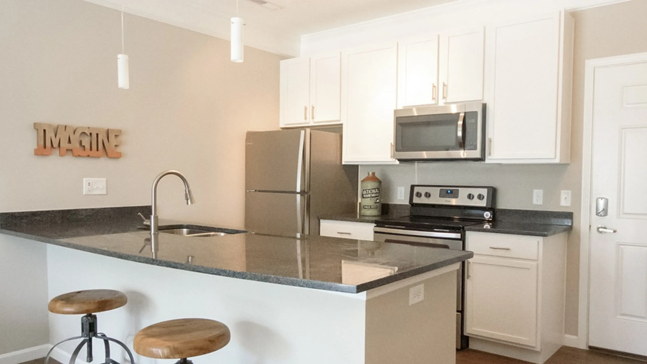 Modern kitchen with sleek white cabinets, stainless steel appliances, chic island, and stylish bar stools.