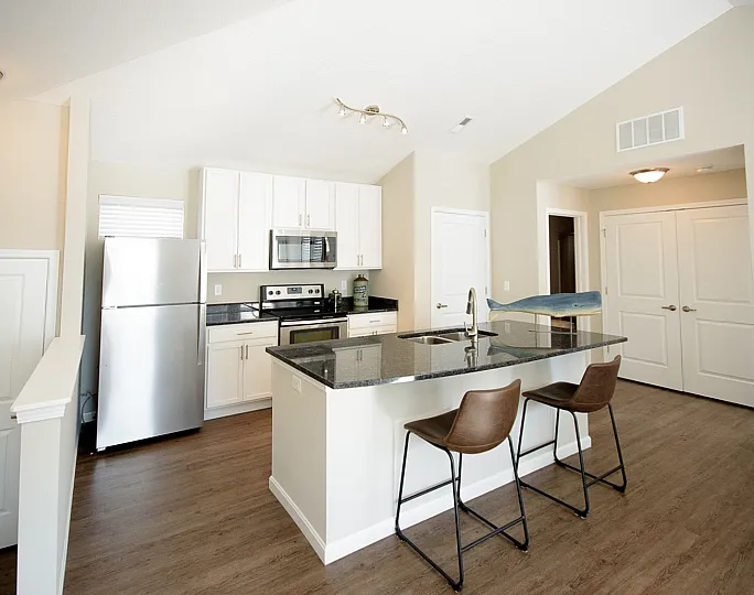 Modern kitchen with sleek granite countertops, stainless steel appliances, and comfortable bar seating.