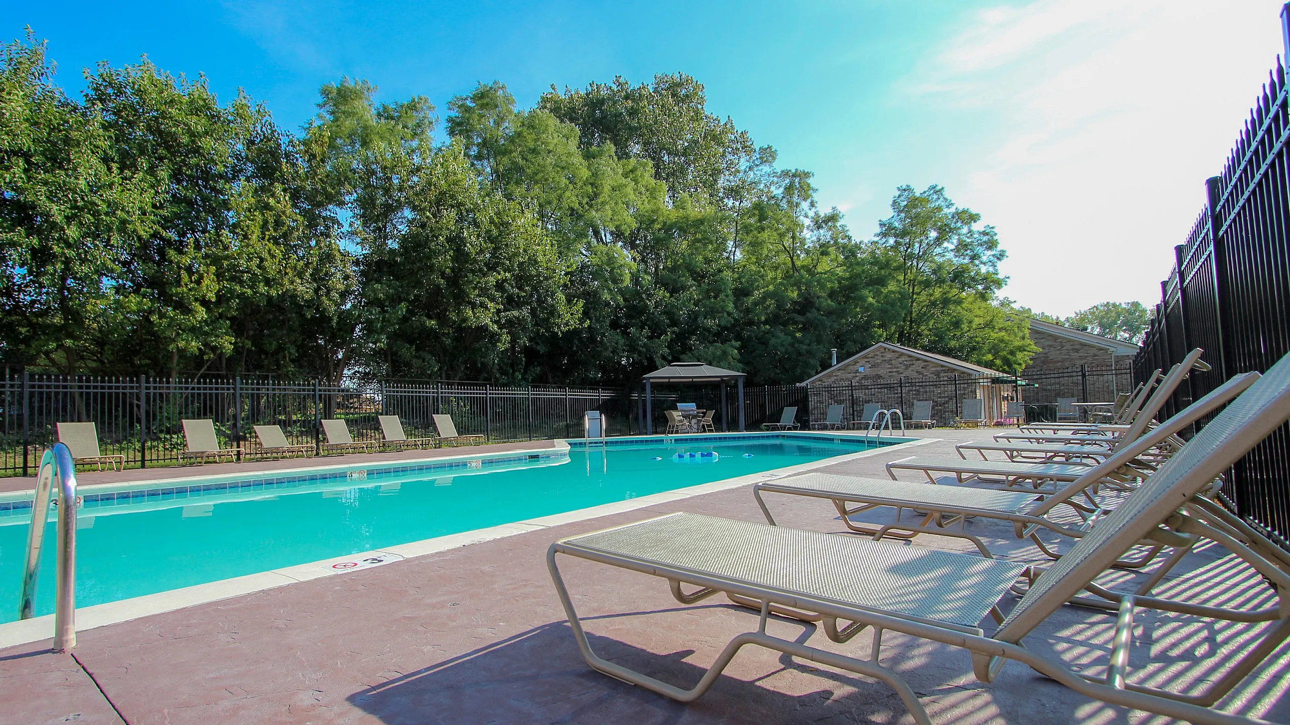 Inviting outdoor pool area surrounded by lush greenery and comfortable sun loungers, perfect for relaxation and leisure activities.