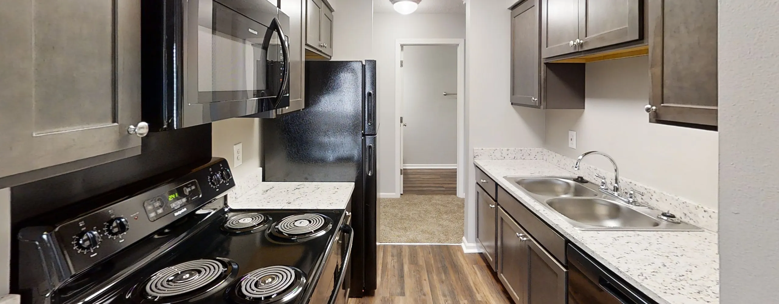 Modern kitchen with sleek black appliances, elegant cabinetry, and polished countertops offering a stylish and functional cooking space.