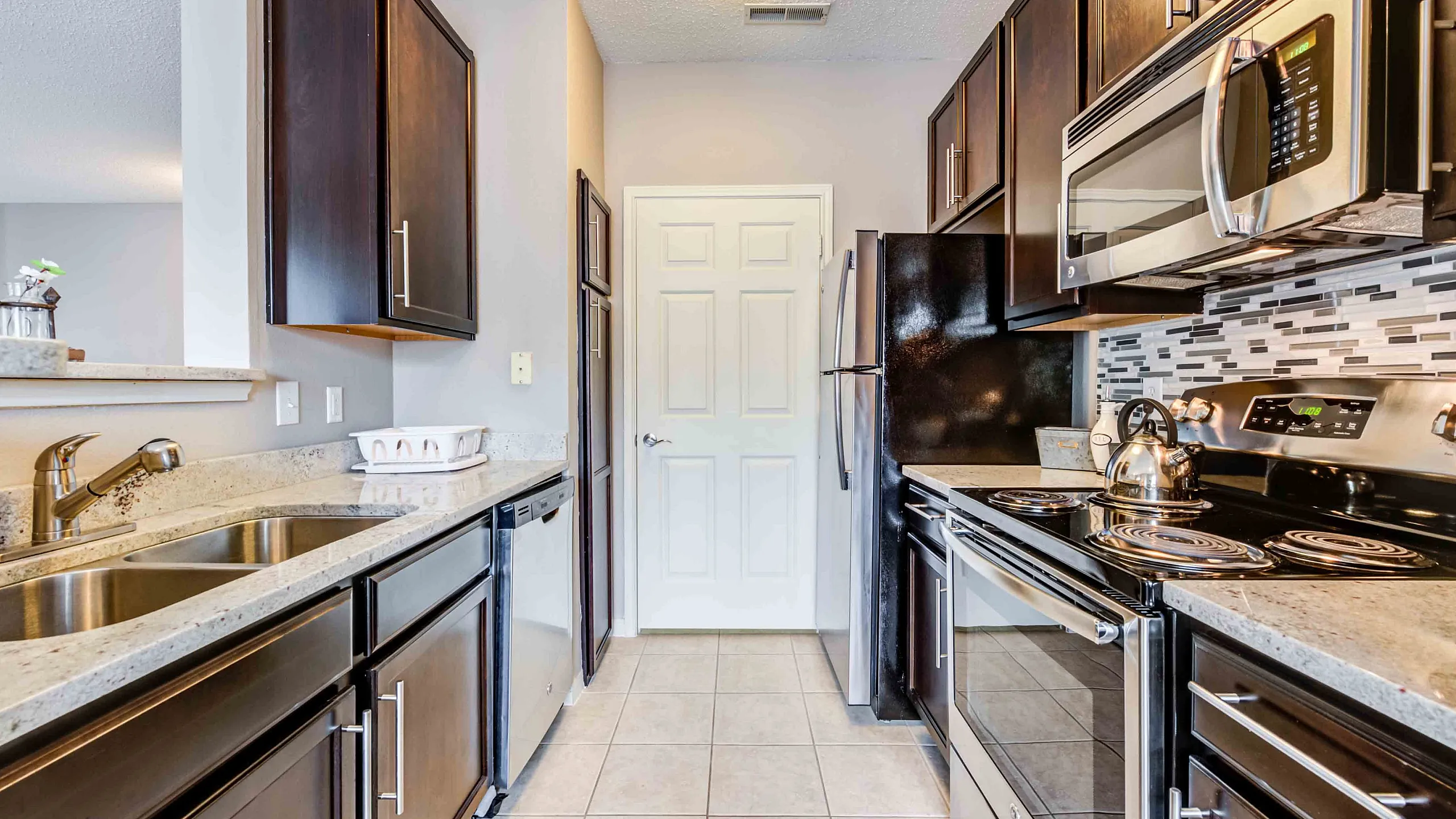 Modern kitchen with elegant dark wood cabinetry, stainless steel appliances, and sleek granite countertops.