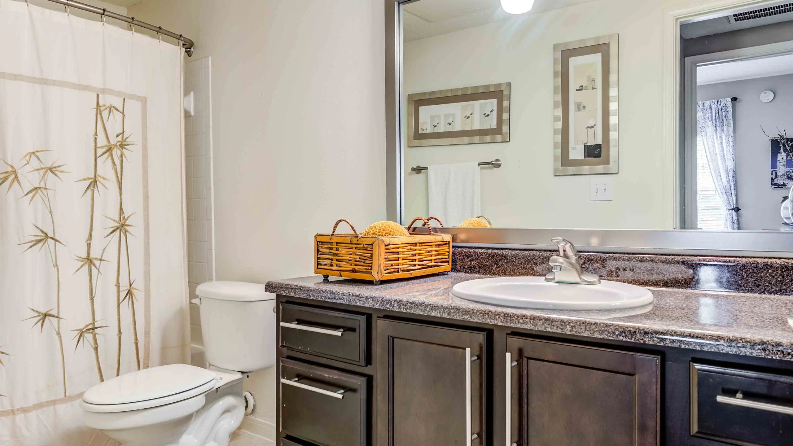 Grande Reserve at Geist Elegant bathroom with sleek countertops, modern sink, and bamboo-themed shower curtain, accentuated by warm lighting.