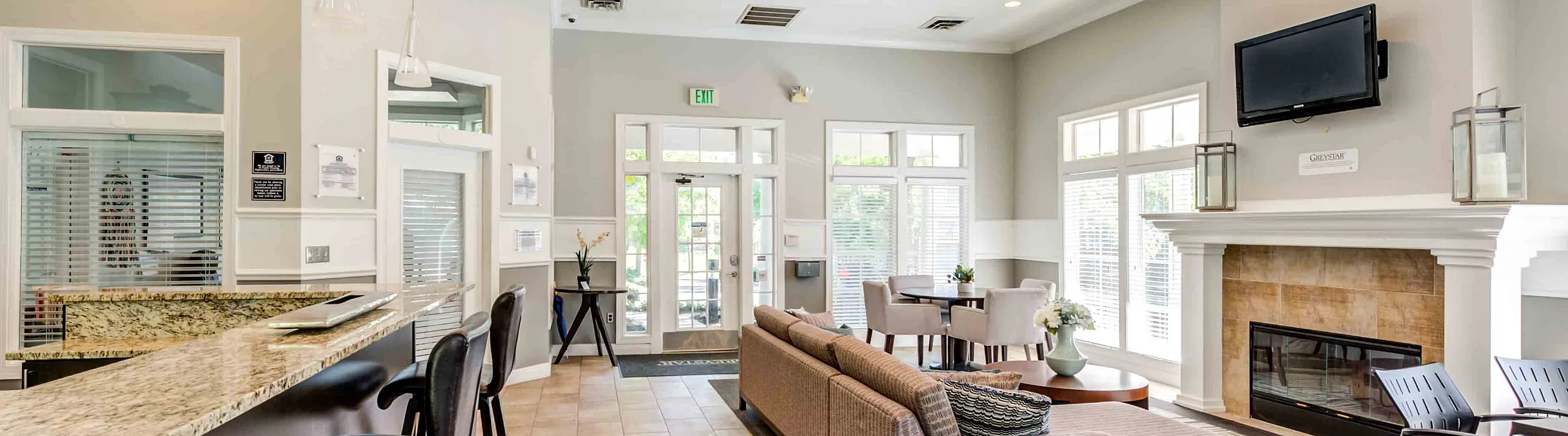 Grande Reserve at Geist Elegant community lounge with modern seating, cozy fireplace, and sleek granite bar area, offering a welcoming and stylish atmosphere.