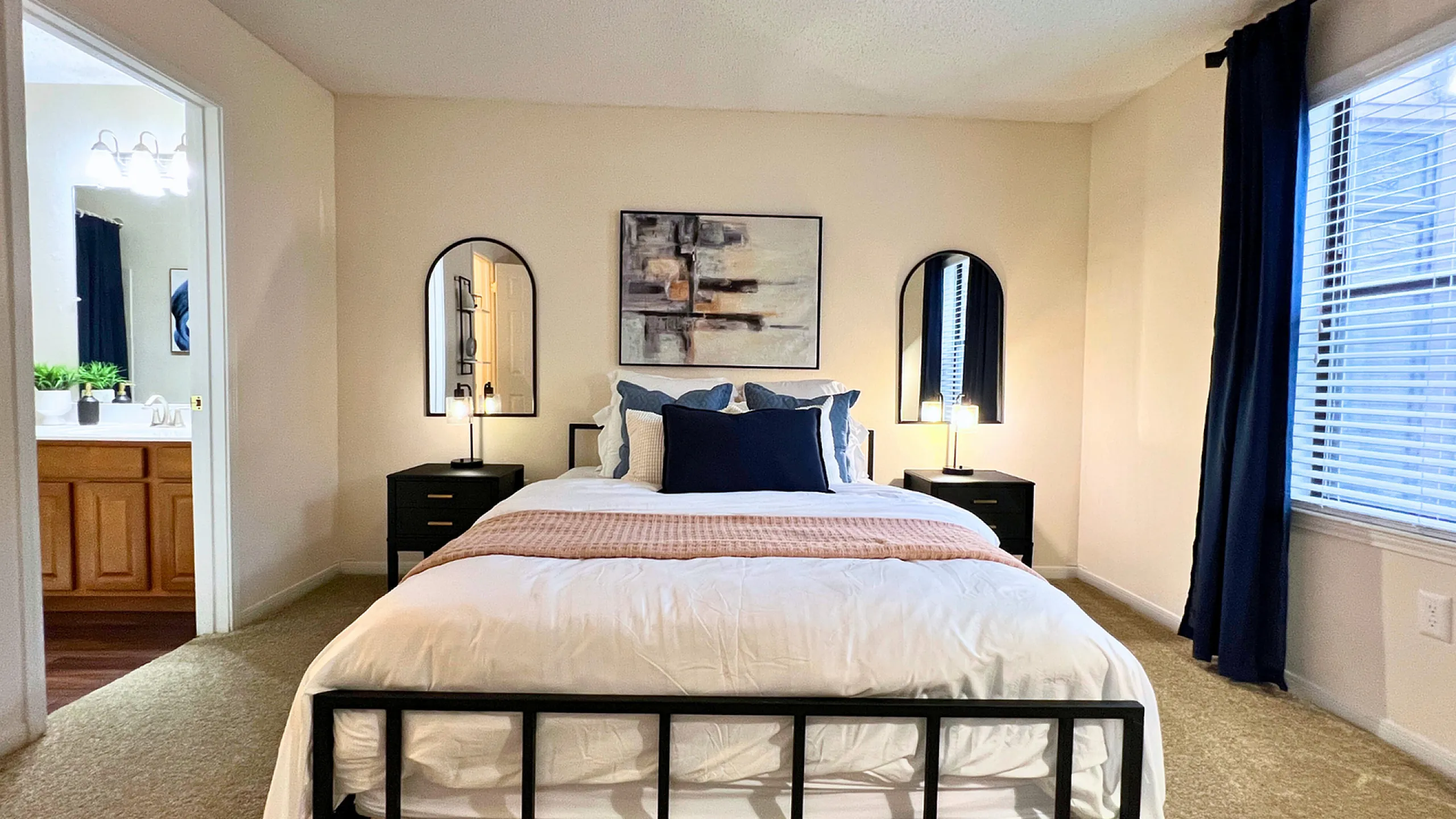 Inviting bedroom with plush bedding, modern decor, and soft lighting, connected to an elegant en-suite bathroom.