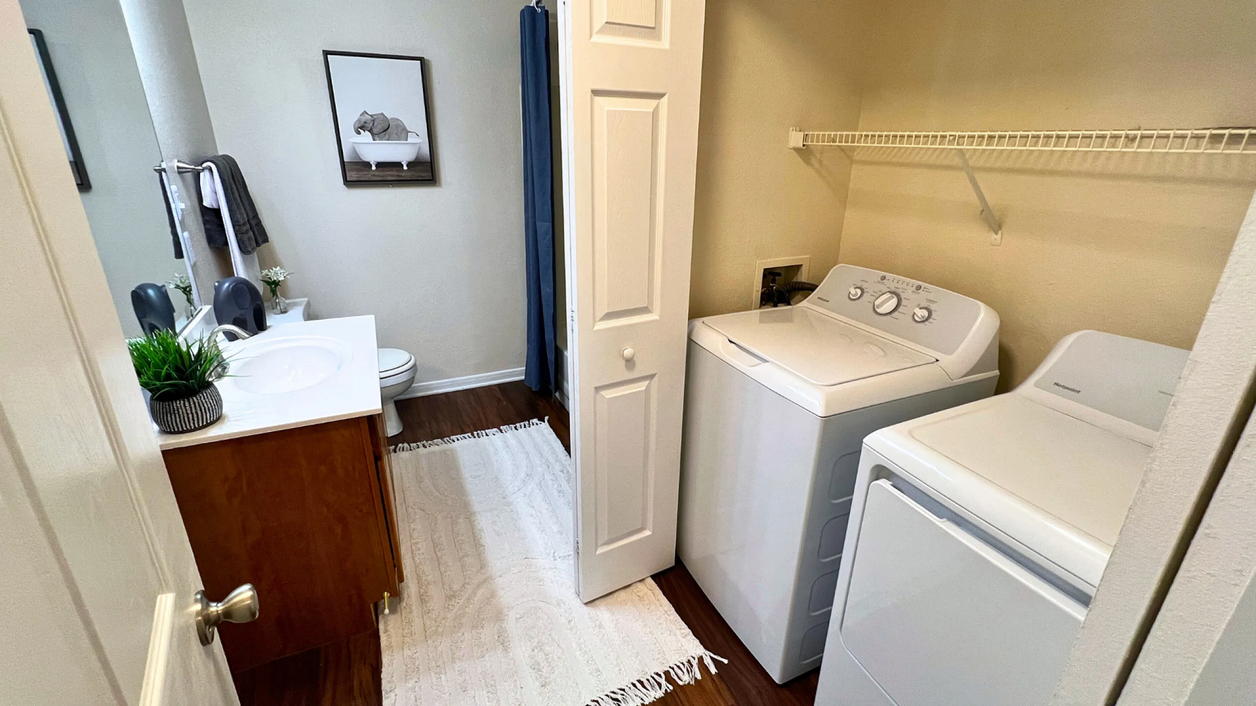 Modern bathroom with sleek vanity, integrated laundry area, and warm hardwood flooring.