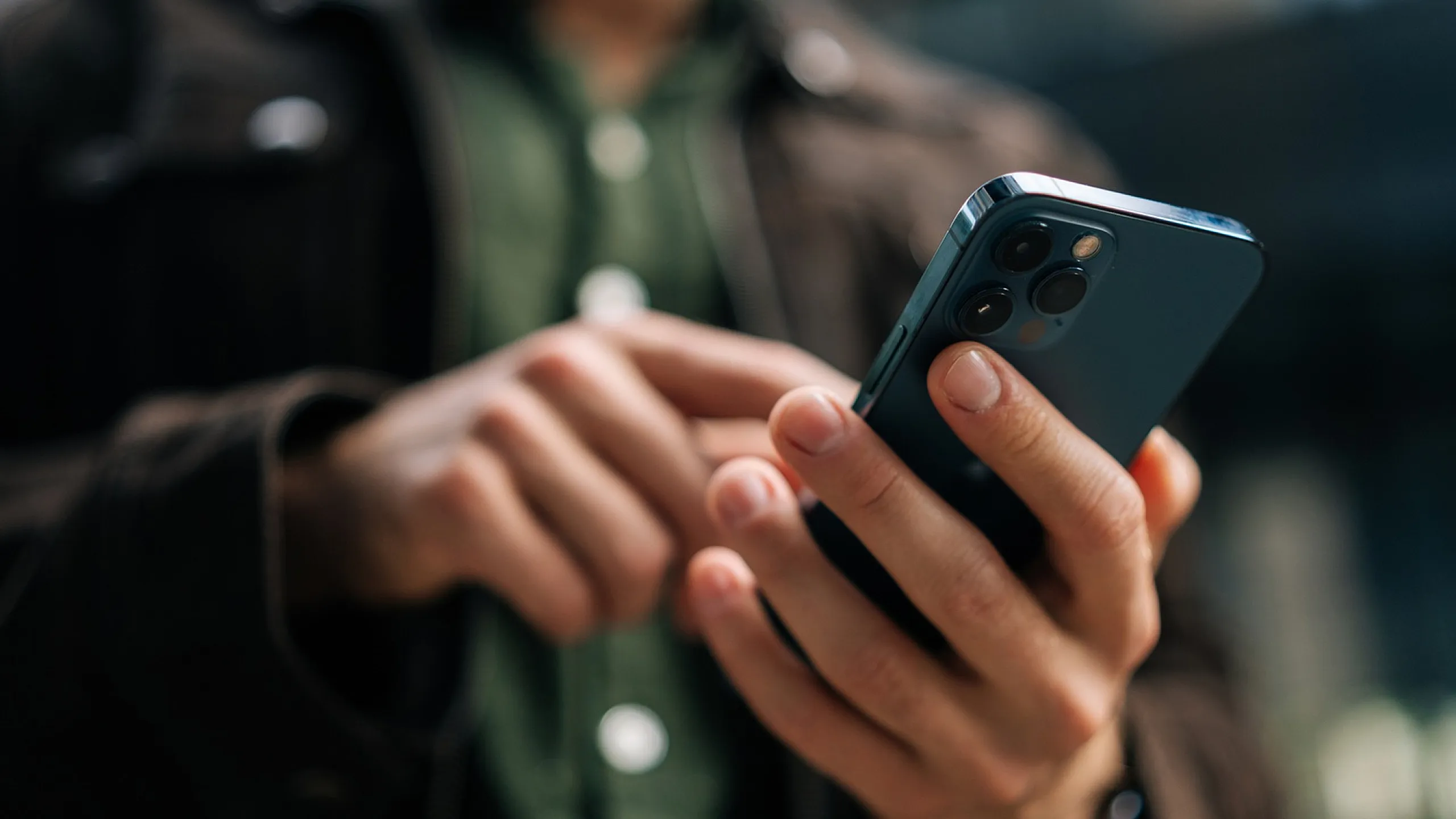 Close-up of a smartphone in a person&rsquo;s hands, capturing modern technology in use outdoors.