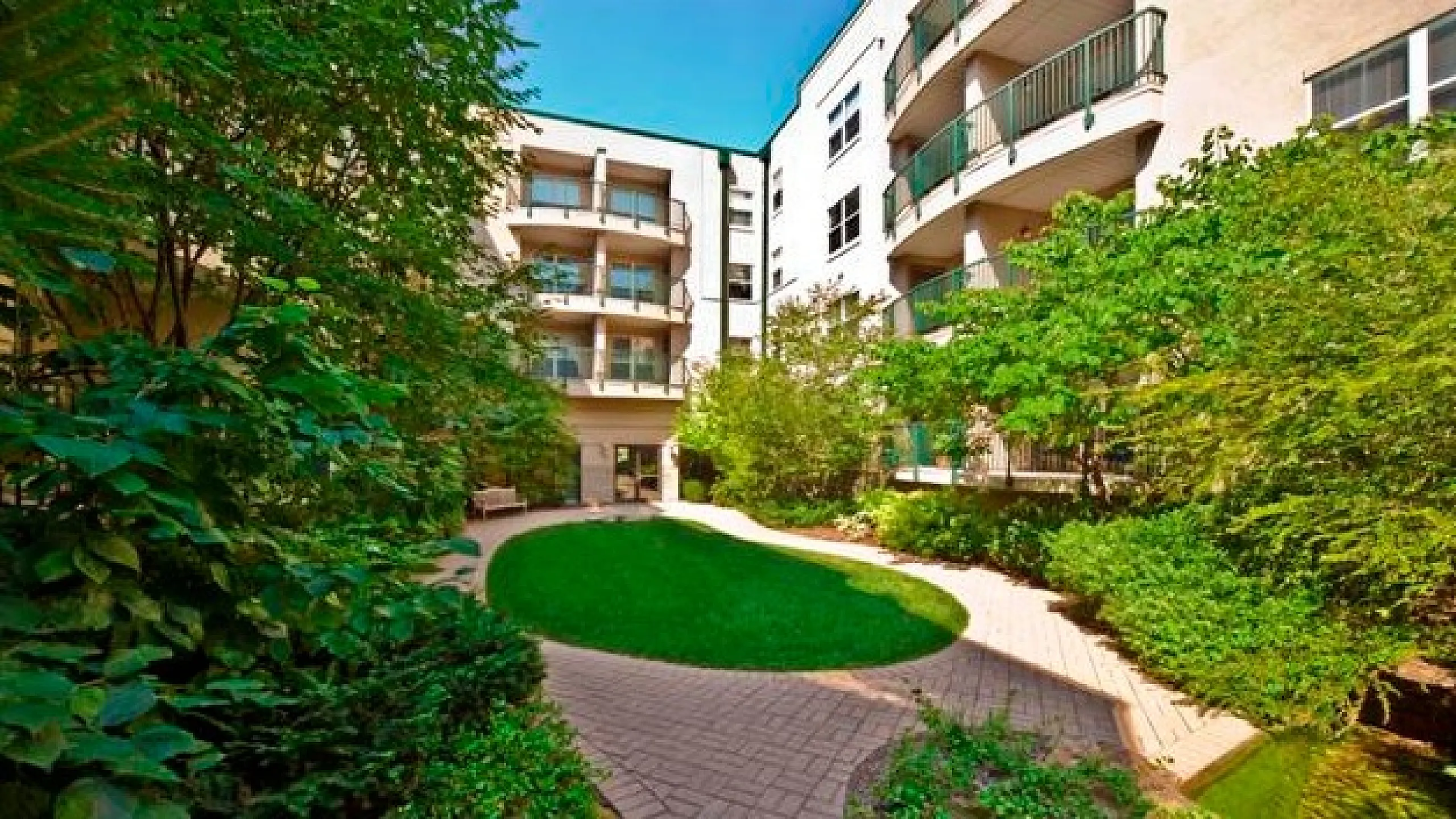 Charming apartment complex with lush greenery and well-maintained courtyard, offering a serene urban living experience.
