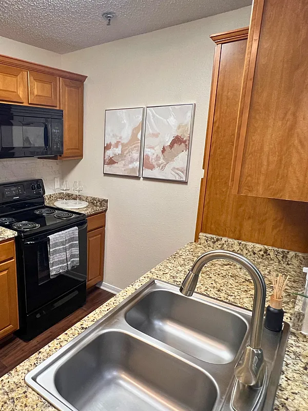 Chic and modern kitchen featuring granite countertops, sleek black appliances, wine rack, and elegant cabinetry.
