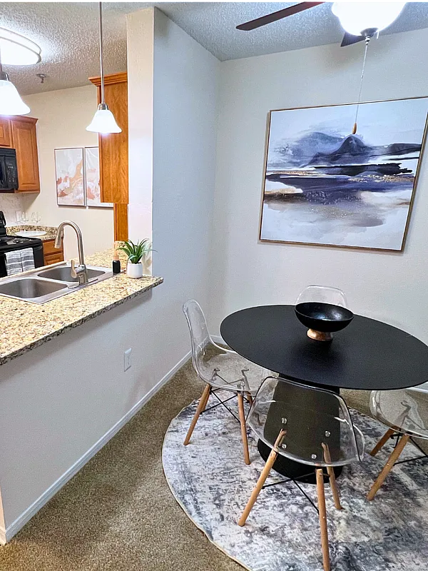 Modern and inviting kitchen and dining area with granite countertops, sleek black appliances, and a cozy dining nook featuring elegant artwork.