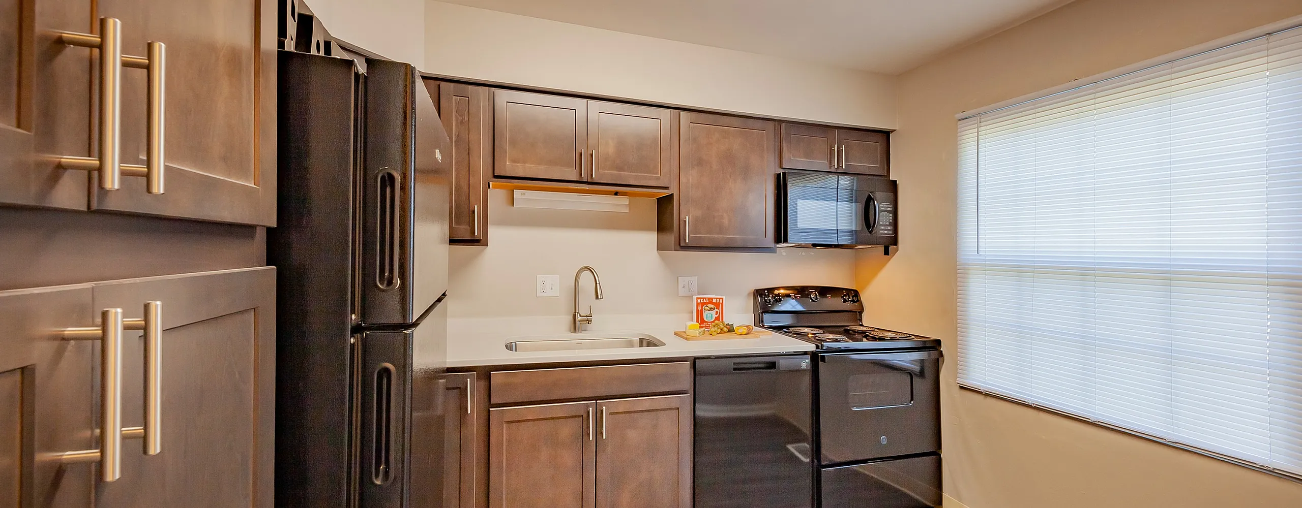 Modern kitchen with dark wooden cabinets, sleek appliances, and abundant natural light.