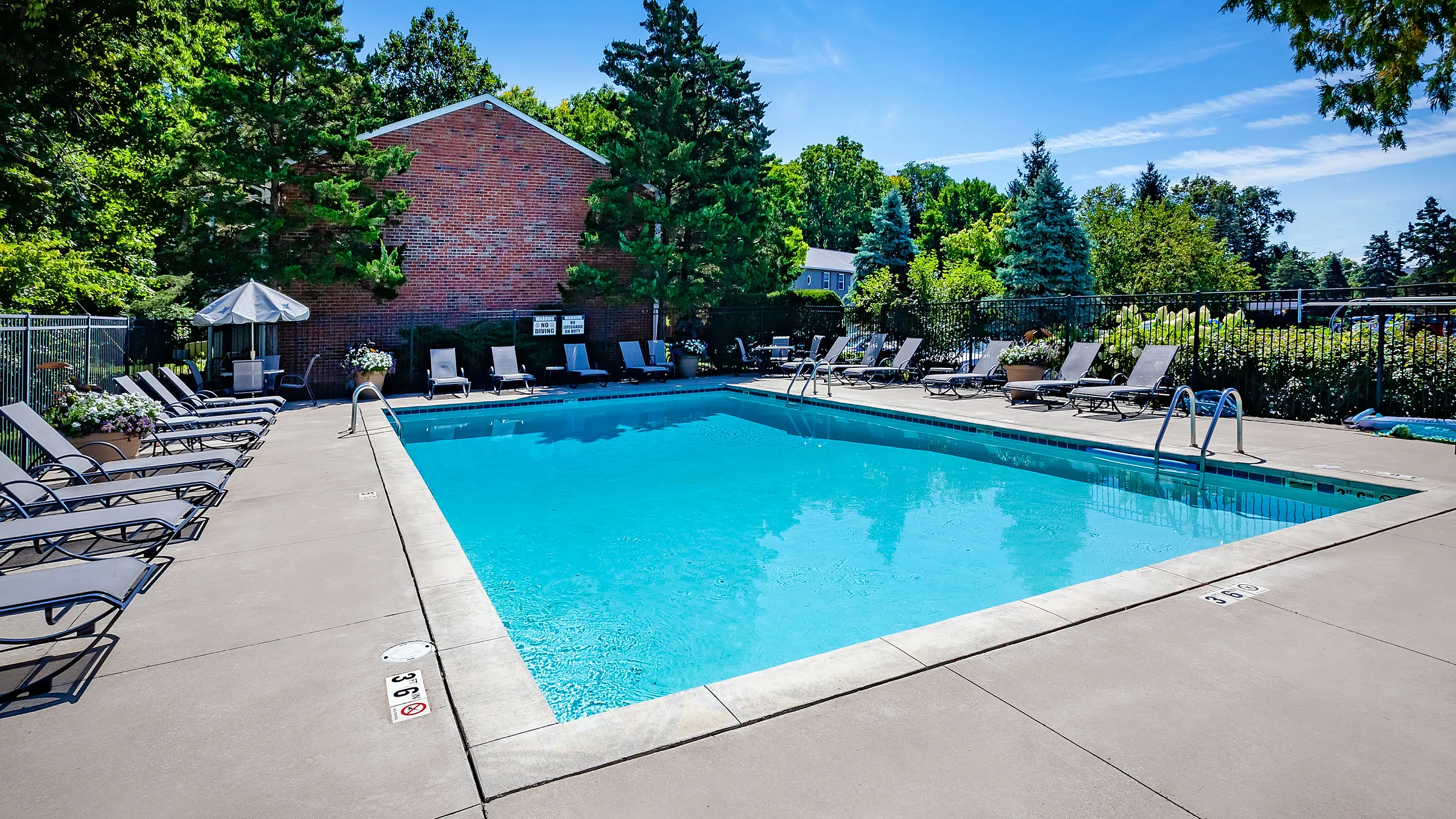 Inviting pool area with abundant lounge chairs, surrounded by lush greenery and a serene atmosphere, perfect for relaxation.