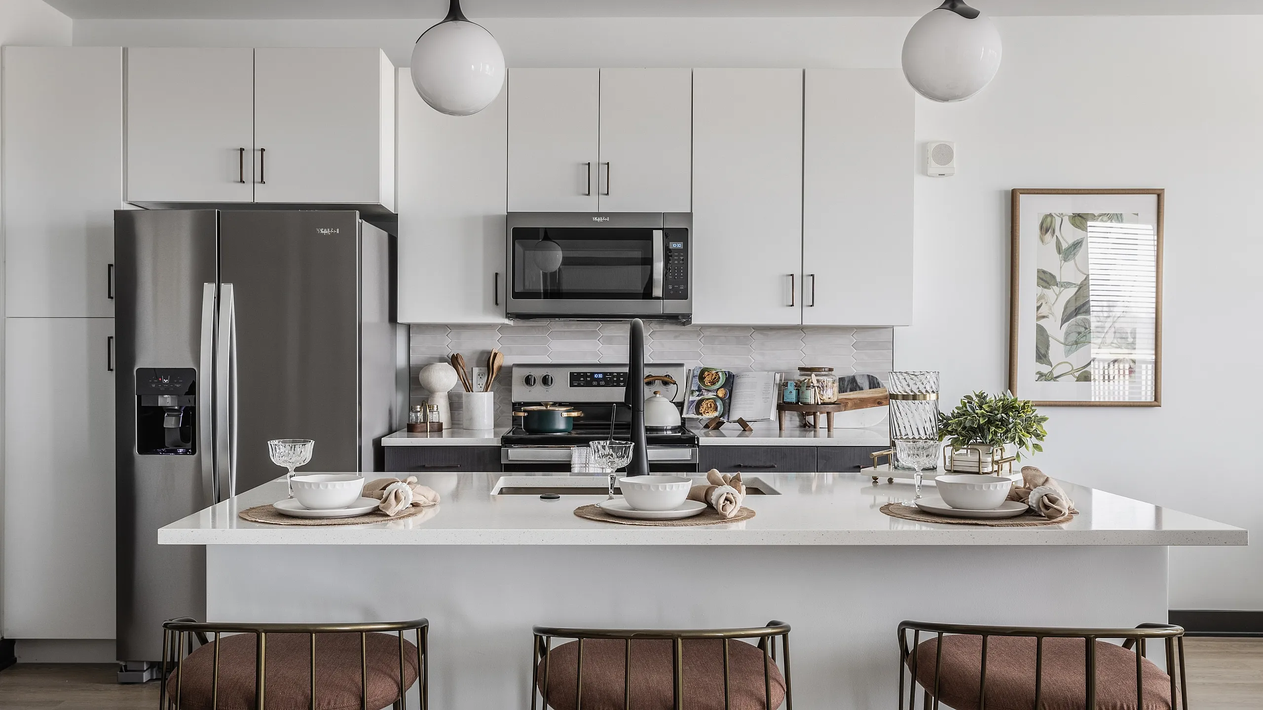 Modern kitchen showcasing sleek appliances, elegant pendant lights, and a chic island with stylish seating.