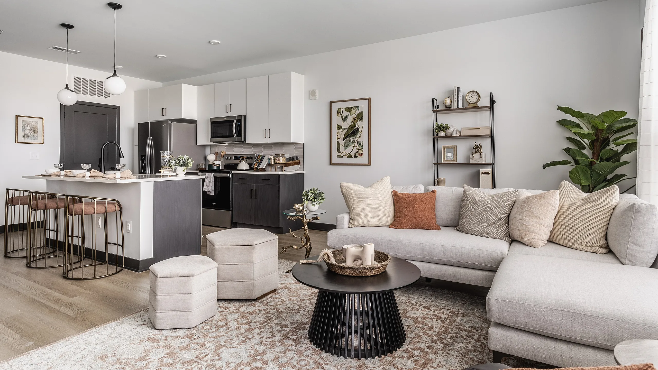 Chic modern living room with cozy sectional sofa, sleek kitchen island with stylish stools, and tasteful decor creating an inviting space.