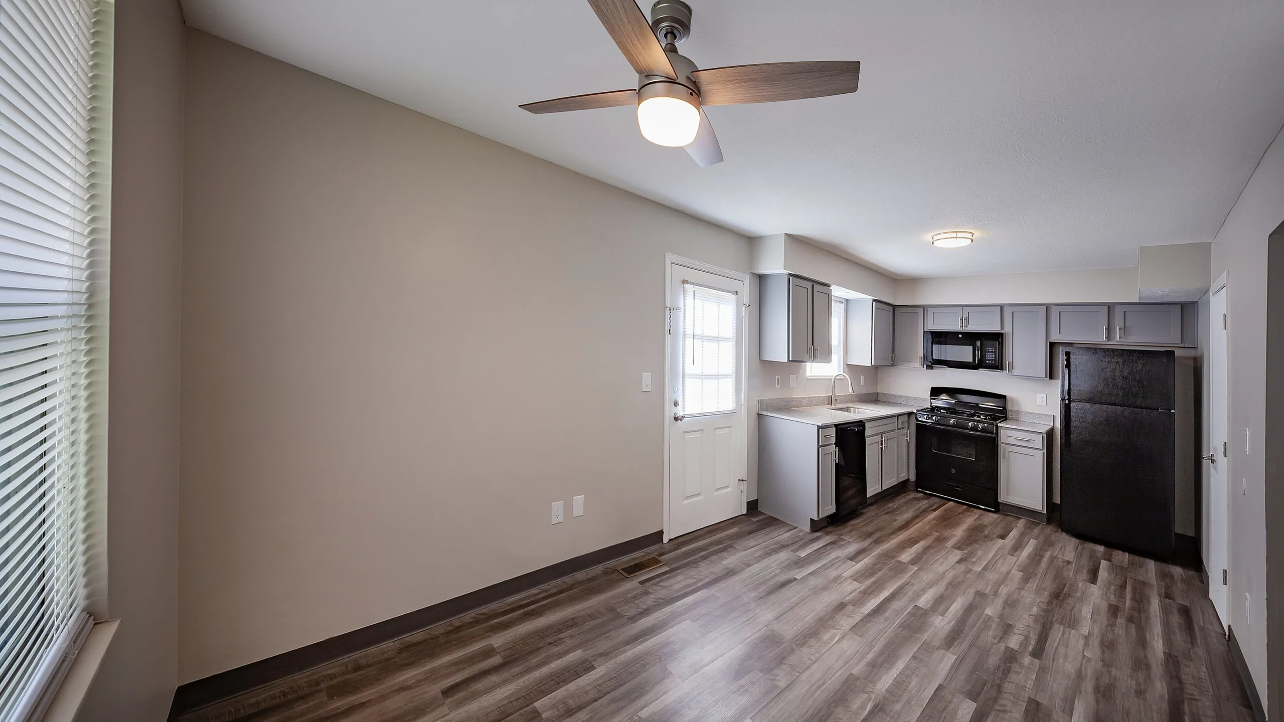 Modern kitchen in an apartment featuring sleek gray cabinetry, a stainless steel oven, and wood-look flooring, perfect for urban living.