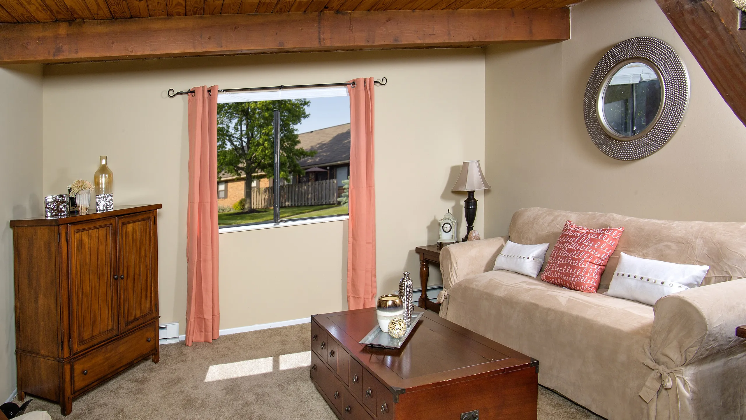 Cozy living room with elegant wooden beams, chic furniture, and a scenic window view, perfect for relaxation and comfort.