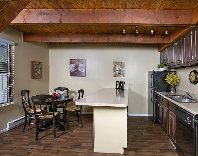 Charming kitchen with rich wood ceilings, a stylish dining area, and modern appliances, offering a cozy and rustic ambiance.