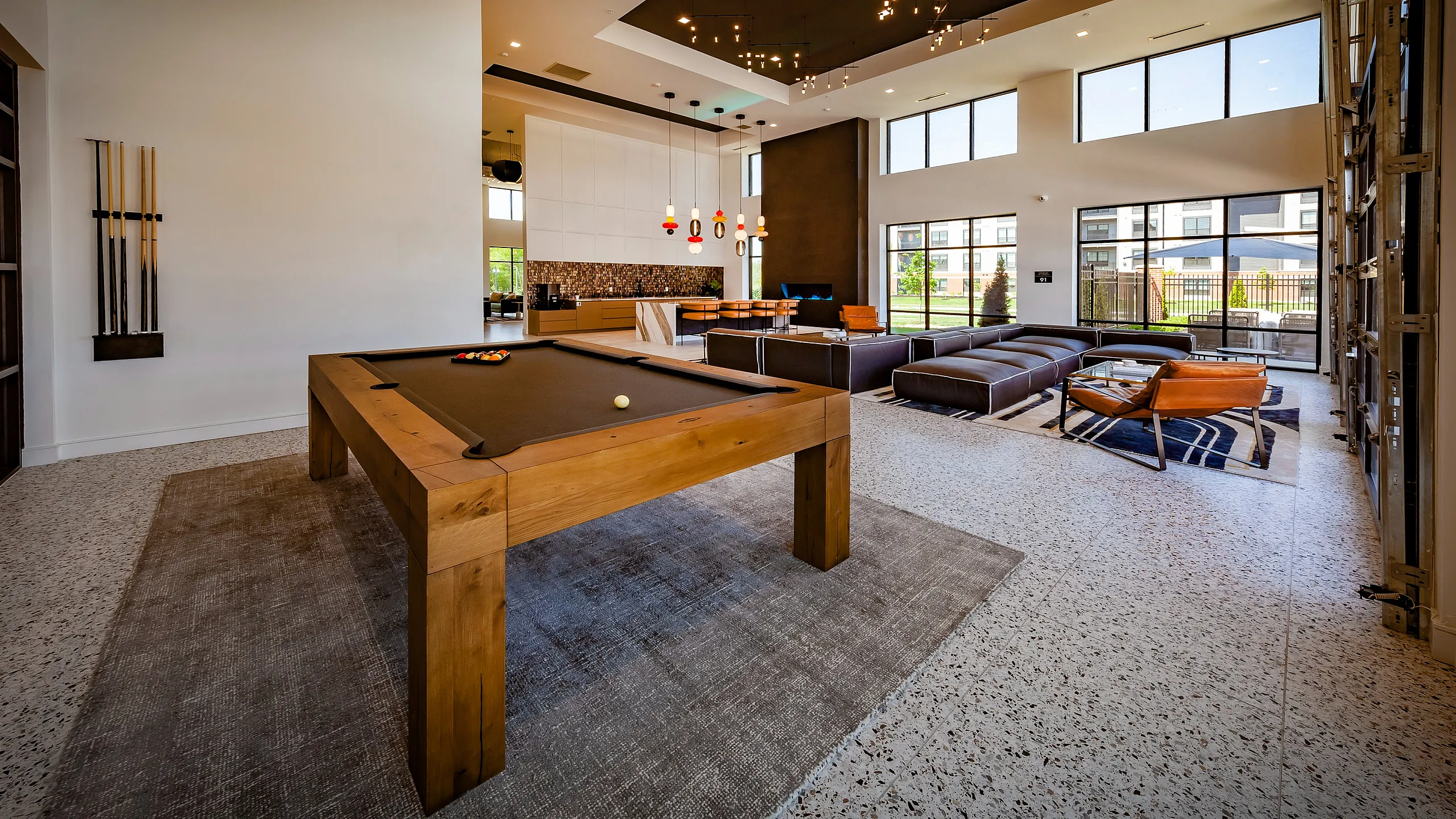 Luxurious modern apartment lounge with a sleek billiards table, stylish seating, and expansive windows for natural light.