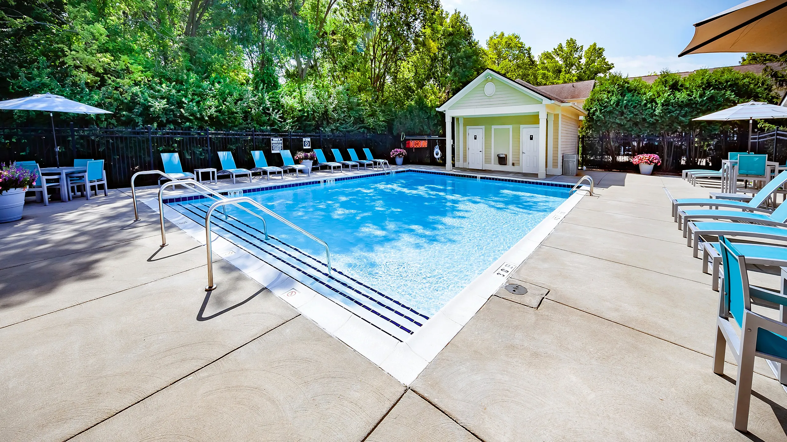 Inviting outdoor swimming pool surrounded by lush greenery and modern lounge chairs, perfect for relaxation and leisure.