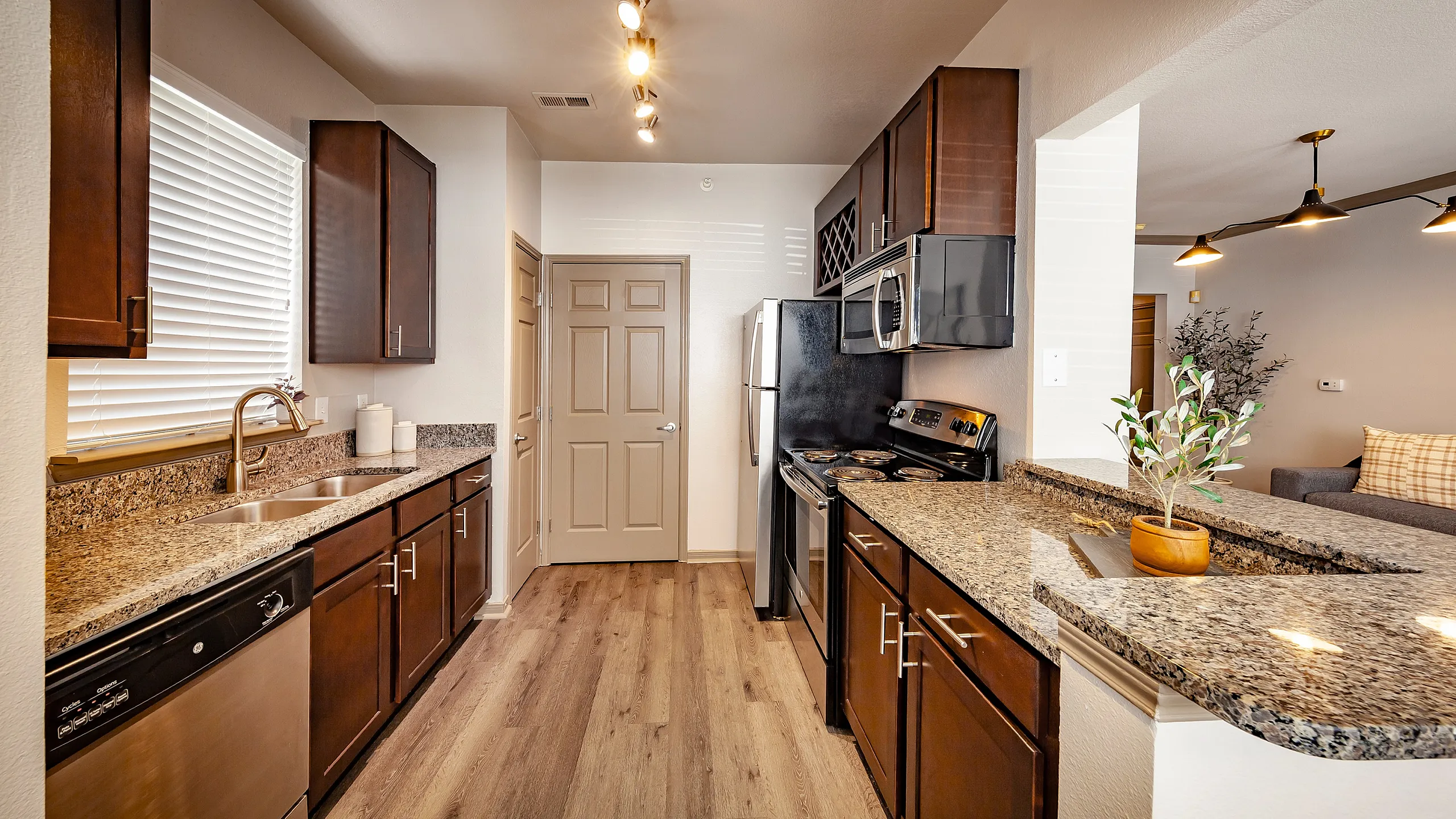 Inviting modern kitchen with granite countertops, stainless steel appliances, and elegant dark wood cabinetry, perfect for culinary enthusiasts.