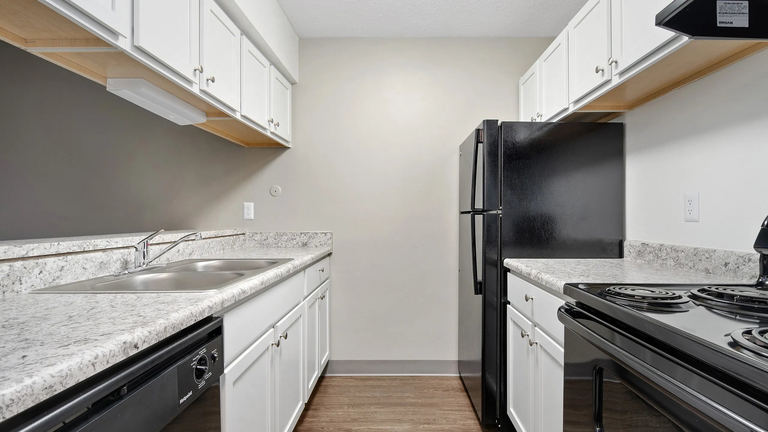 Sleek modern kitchen with elegant black appliances, pristine white cabinetry, and stylish granite countertops.