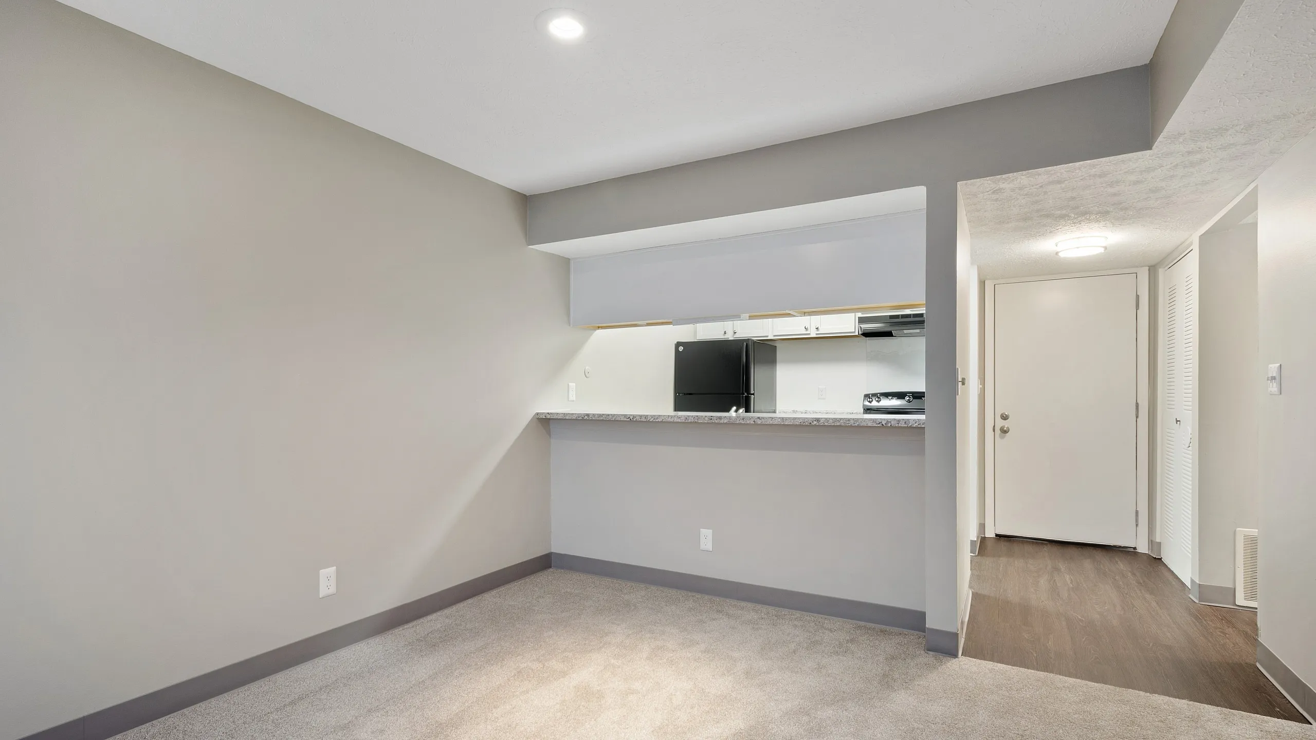 Inviting open-concept apartment showcasing a modern kitchen with bar seating, sleek flooring, and neutral tones.