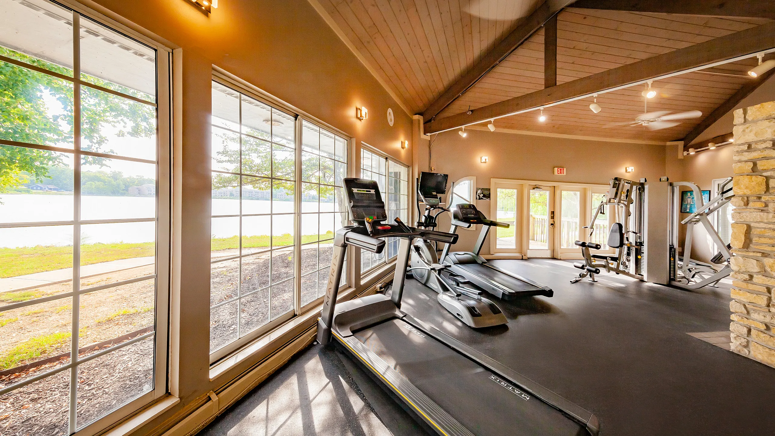 Bright and inviting gym with modern equipment and large windows offering stunning lake views.