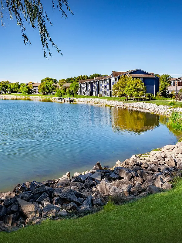 Idyllic lakeside apartment community with lush greenery, modern architecture, and serene water views, perfect for tranquil living.