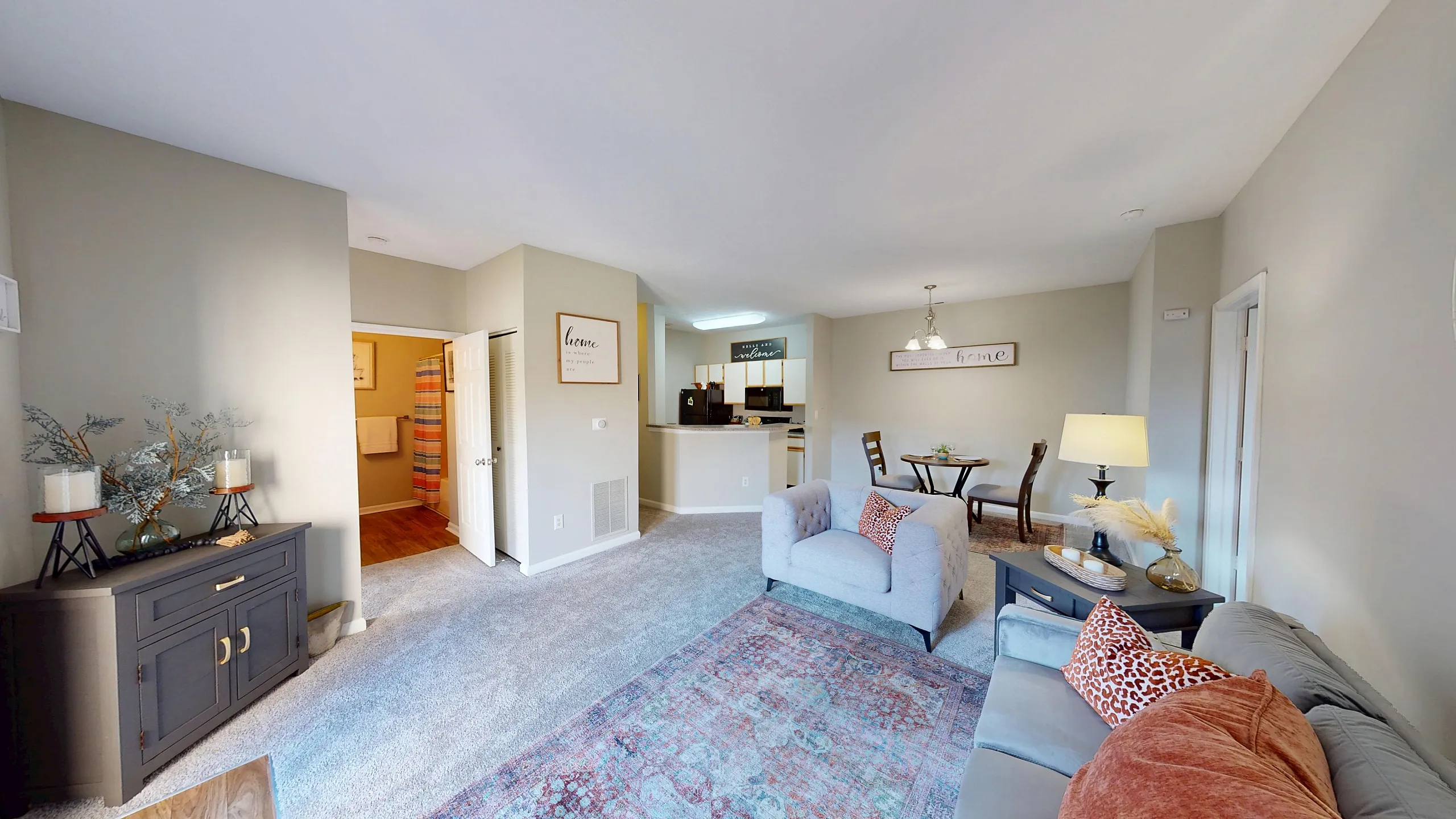 Cozy living room with plush seating, elegant decor, and a bright open layout leading to a dining area and kitchen.
