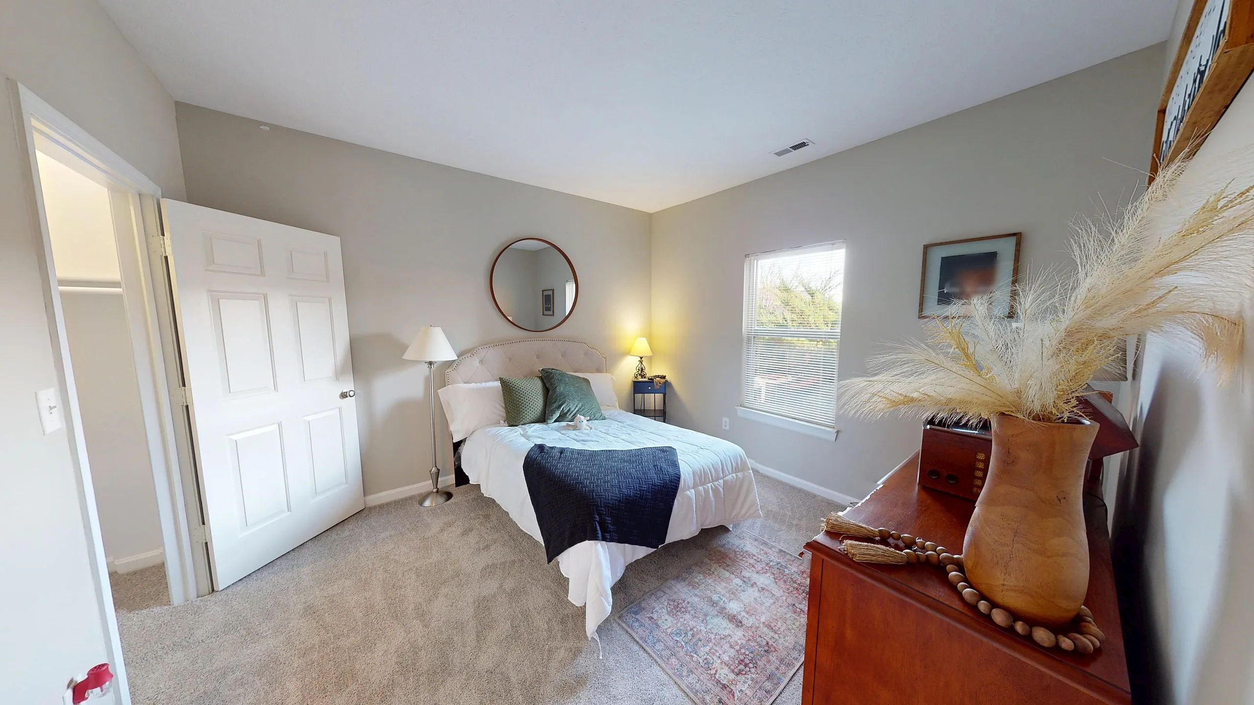 Cozy bedroom with soft carpet, stylish decor, and a large window inviting natural light.