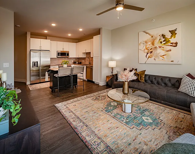 Contemporary open-plan living space featuring a modern kitchen with stainless steel appliances, a cozy lounge area with elegant decor, and stylish lighting for a warm ambiance.