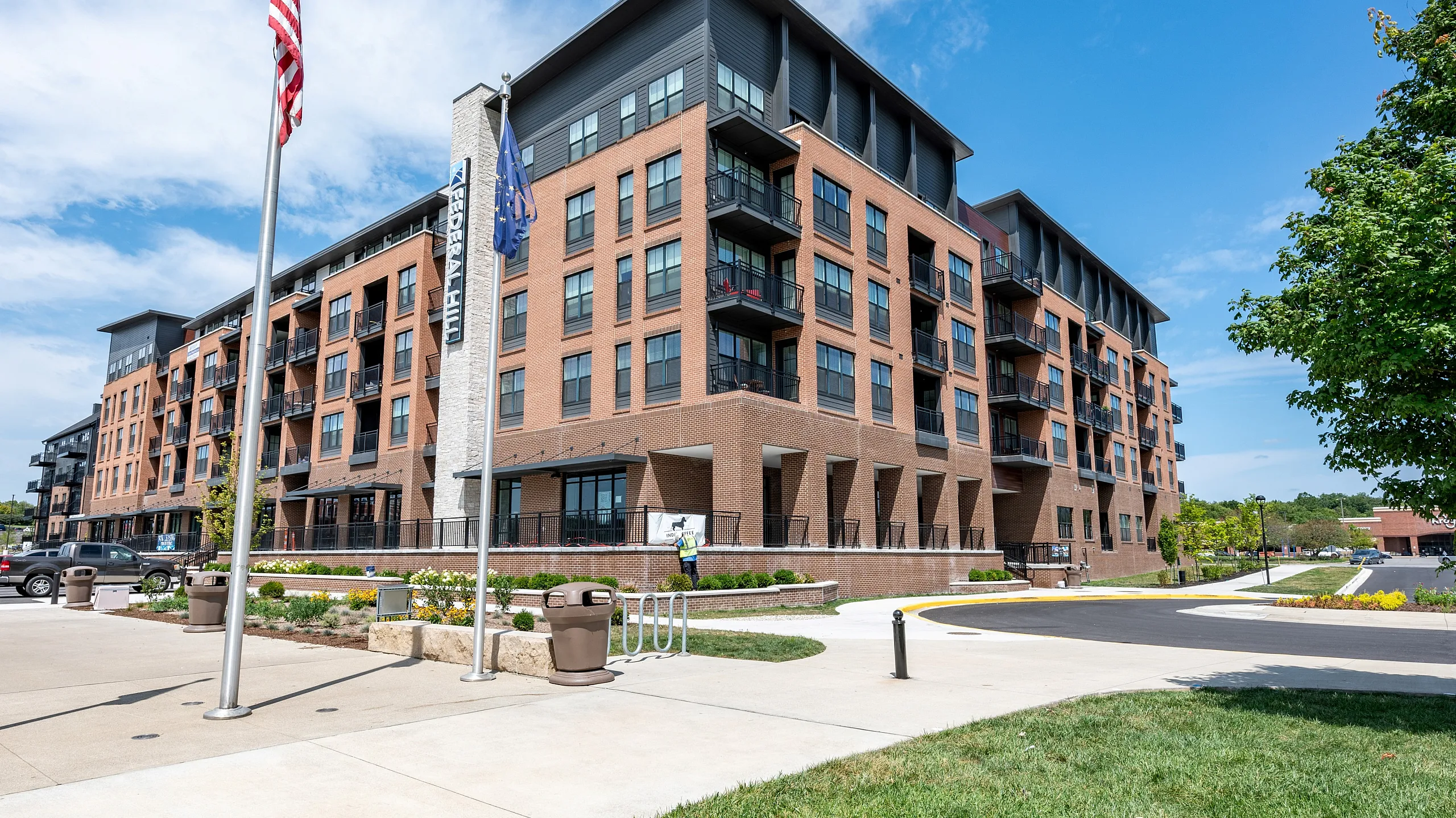 Modern brick apartment complex with multiple balconies, set against a clear sky, featuring beautiful landscaping and a welcoming entrance.
