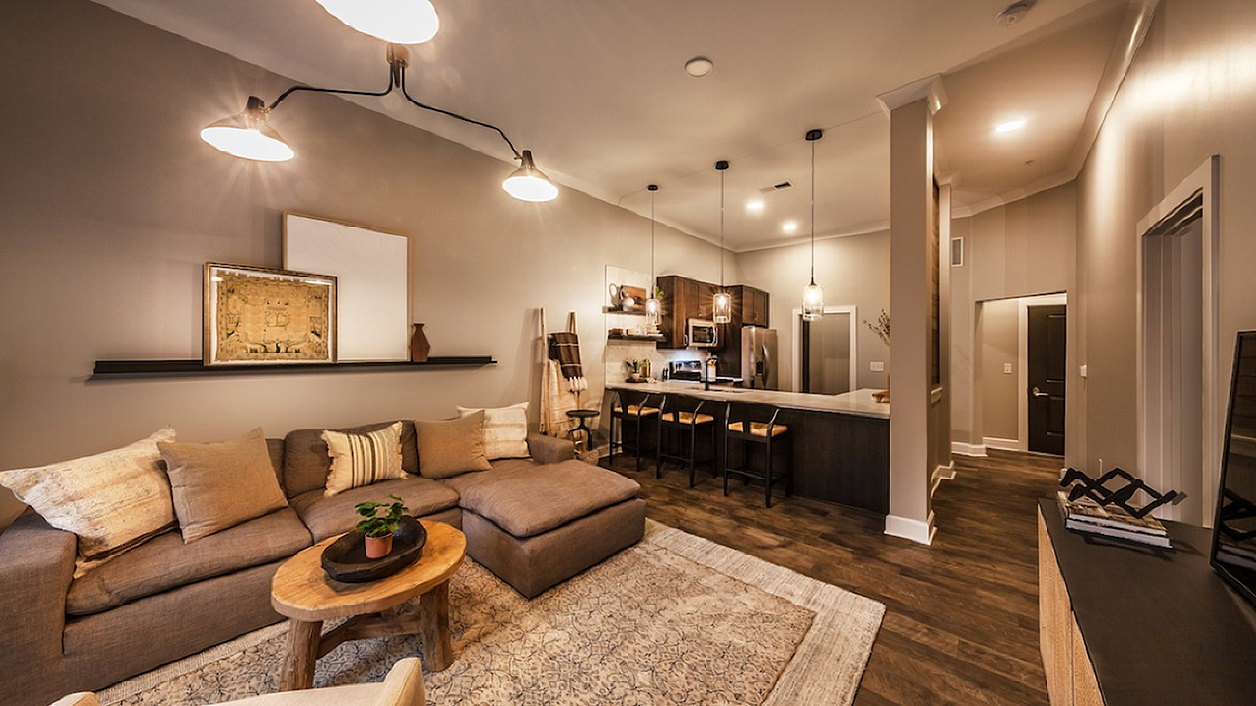 Elegant open-concept living room with cozy sectional sofa and stylish kitchen island, accented by warm lighting and modern decor.