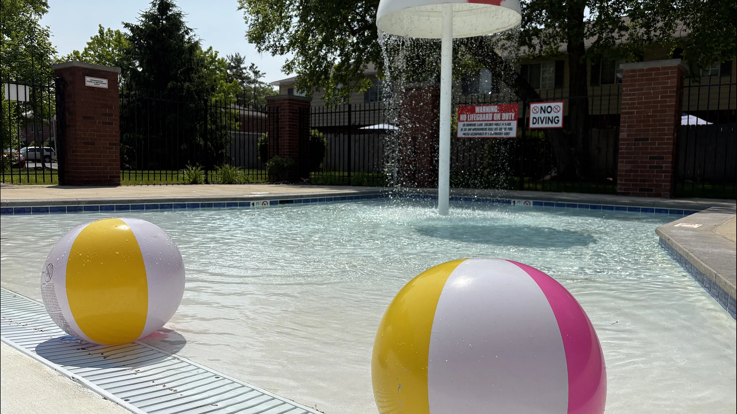 Inviting outdoor pool area with colorful beach balls and a unique mushroom fountain, perfect for family relaxation.