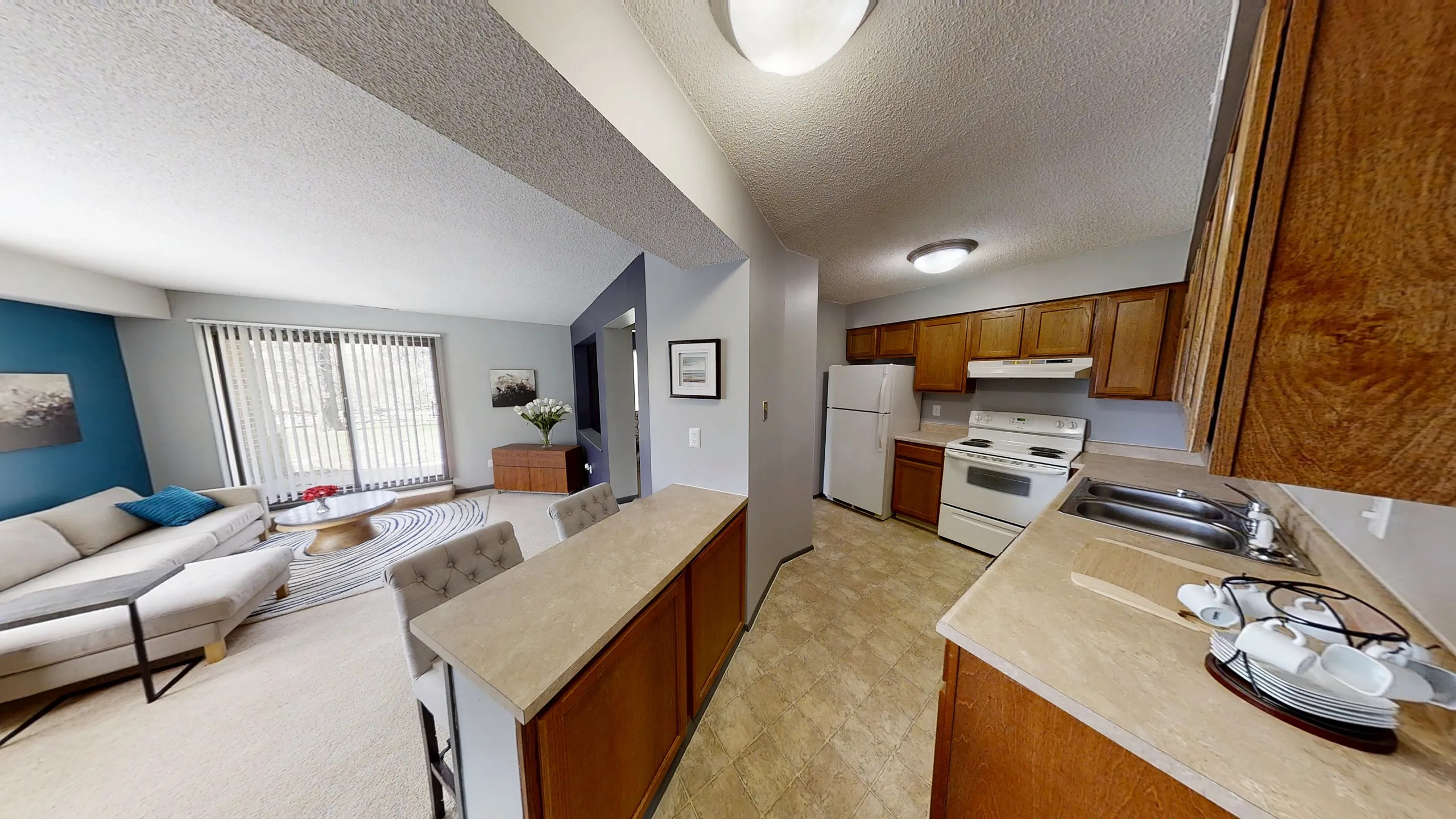 Landmark Apartments Inviting living area with bright natural light, comfy sectional sofa, and modern kitchen in a cozy open-plan layout.