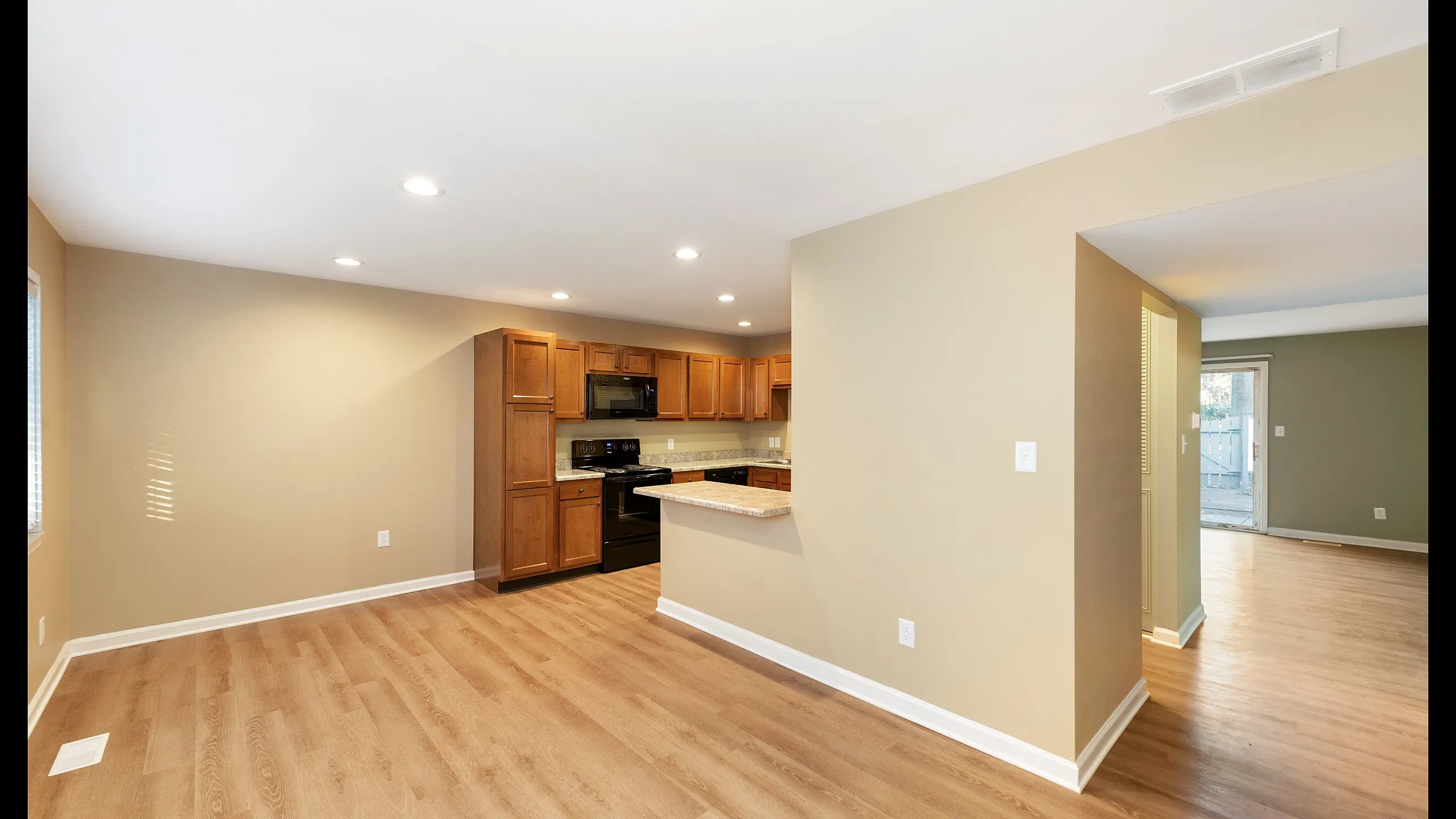 Spacious open-concept kitchen and living area featuring elegant wood flooring, sleek appliances, and natural lighting.